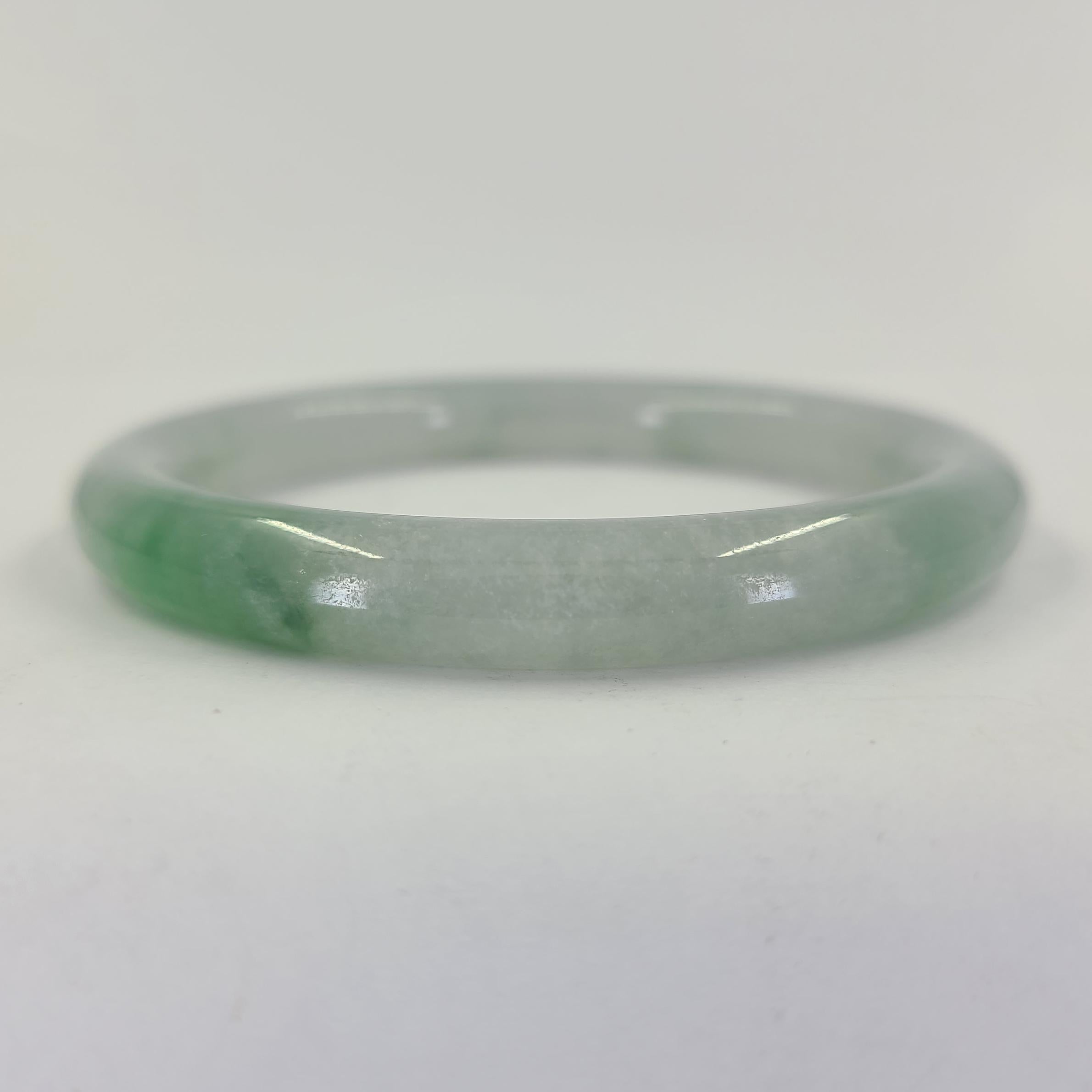 Jadeite Jade Hololith Bangle Bracelet Measuring 8.5mm Wide. Mottled Green Color. Interior Diameter Is 61mm Wide. Finished Weight Is 38.3 Grams.