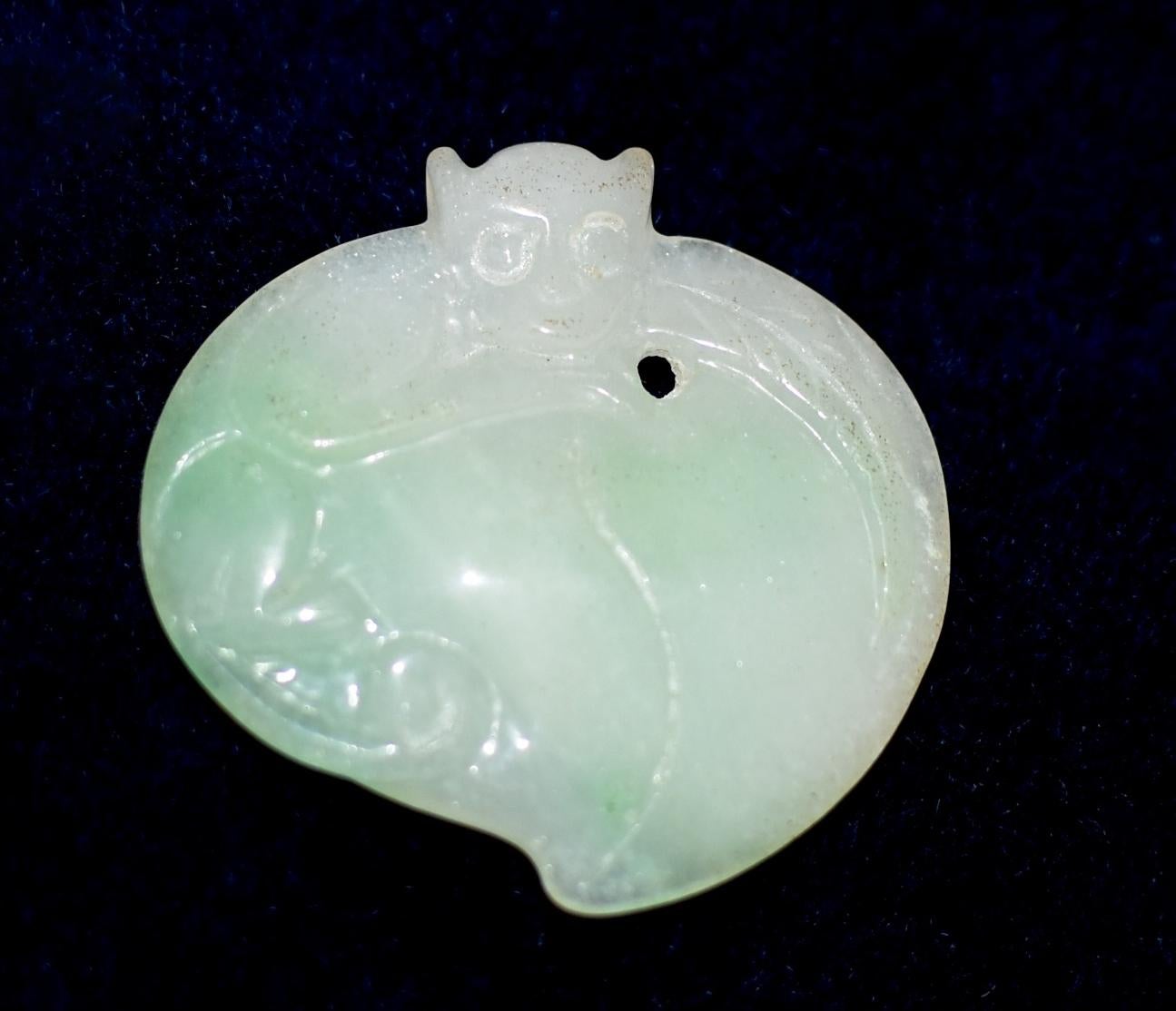 A beautiful jade pendant featuring a monkey perched on a peach. The material is all natural white jadite jade with shades of green. The depiction of the monkey is vivid and adorable. The peach maximized the beauty of the jade, demonstrating its pure