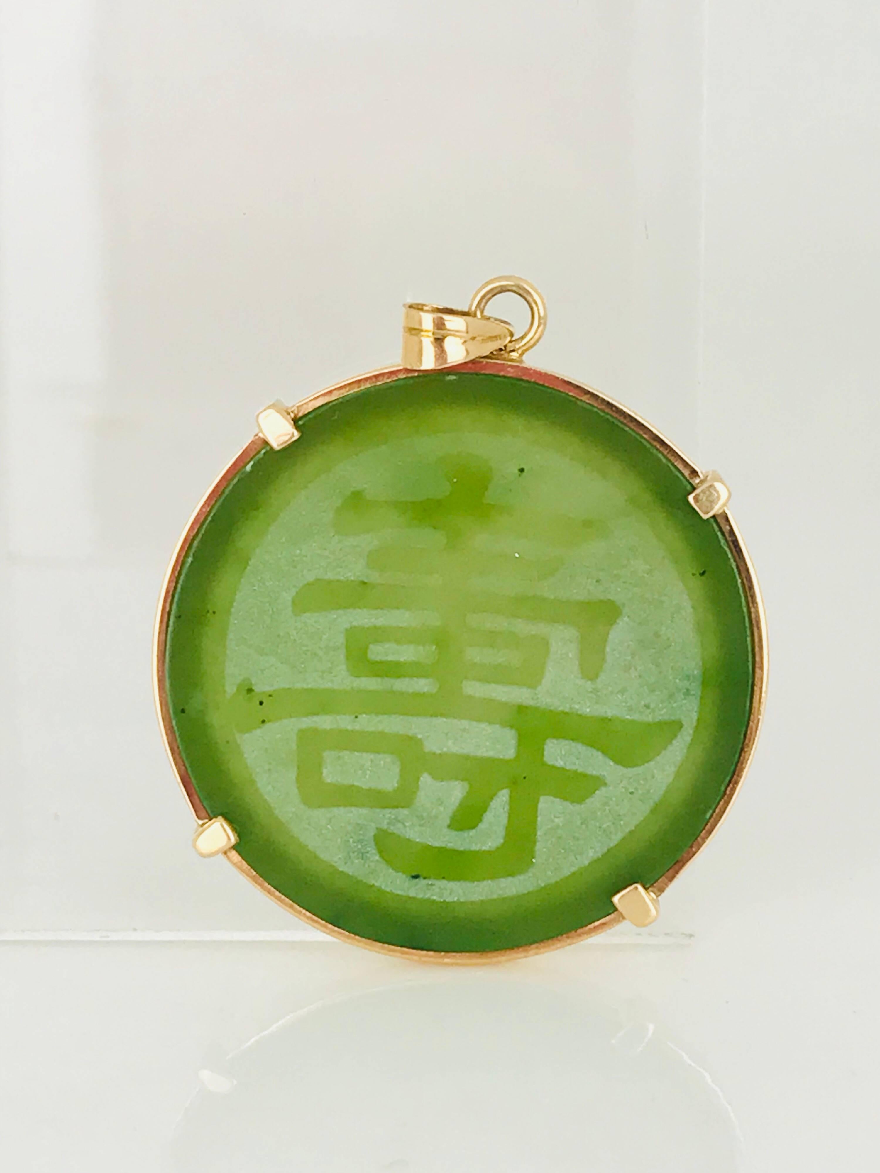 14 Karat, Circle Jadeite Pendant, translucent green with Chinese good luck, symbol etchings. Beautiful, deep color green. 
Circa 1950's 
1.25 inches in diameter, the Jade is nicely protected with gold and set in 4 prongs. 

GIA Gemologist, Inspected