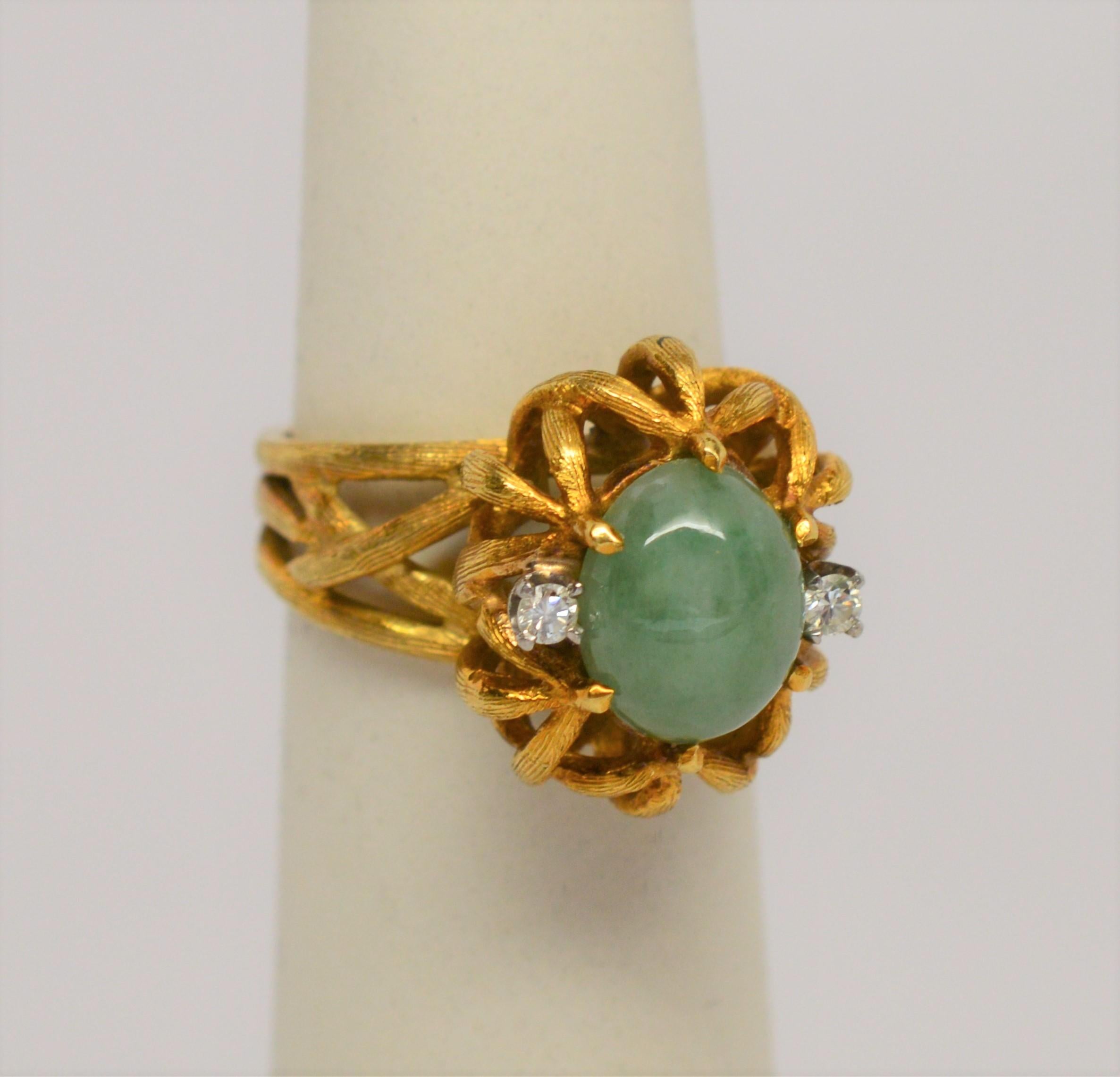 A fine, soft green, mottled semi-transparent Imperial Jadite Cabochon set in a gloriously hand-crafted 18 Karat brushed Yellow Gold Ring with two .04 carat Diamonds side lights. Unusual shank construction of three separate pieces assembled into a