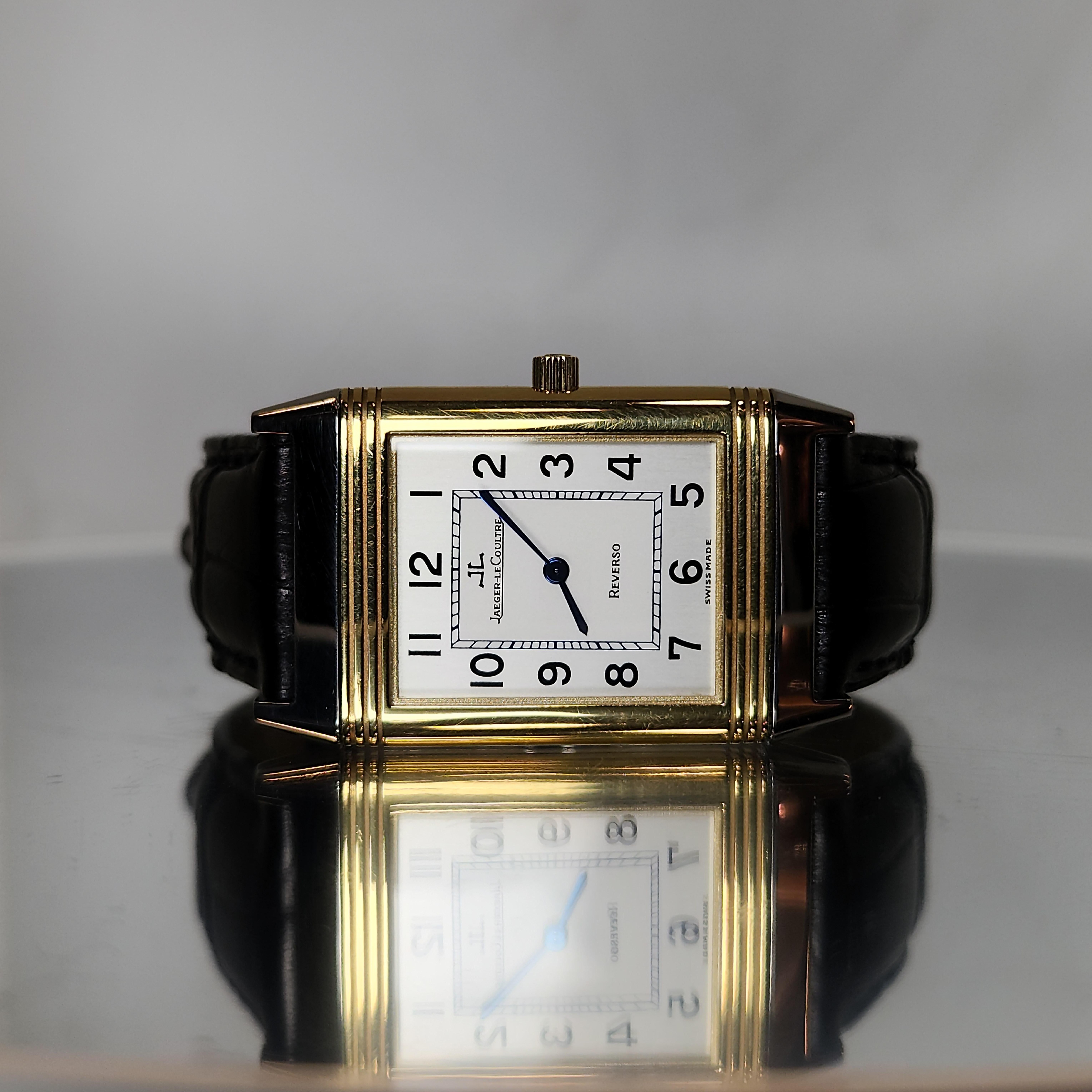 Jaeger Lecoultre stainless steel and 18 karat gold reverso classique wristwatch . Mechanical,  rectangular silver tone dial with black arabic numerals and minute indicators, sapphire crystal,  reversible cover. Case diameter 39 × 23 mm, black