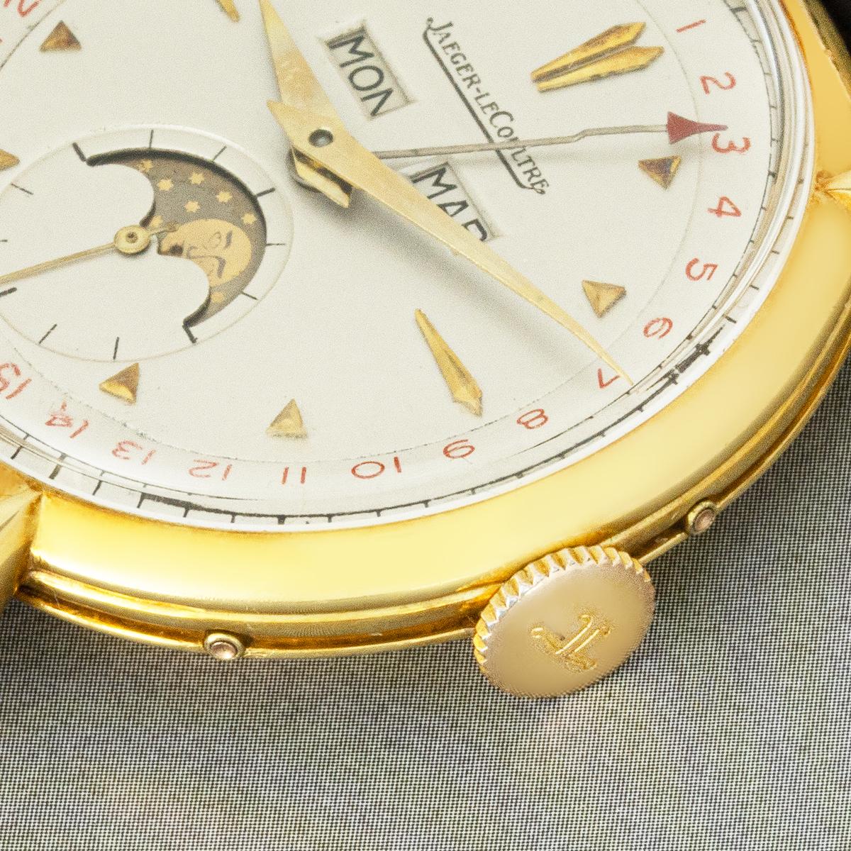A stunning vintage Jaeger-LeCoultre Triple Calendar Moonphase men’s wristwatch, crafted from 18k yellow gold and powered by a manual wind movement.

Its elegant silver dial features sleek pyramid-shaped hour markers, along with weekday and month
