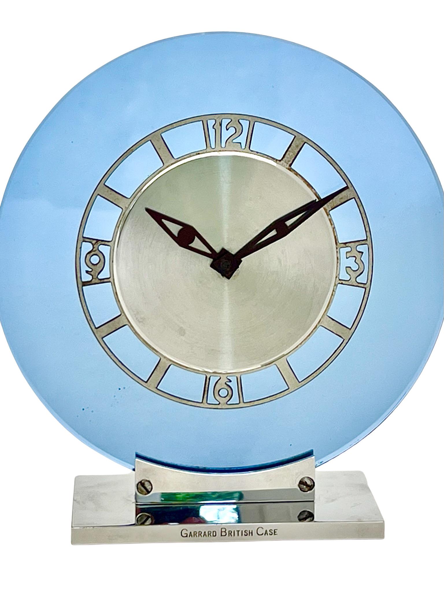 A stylish Art Deco chrome and cobalt-blue glass eight day mantel clock by renowned Swiss watchmaker Jaeger LeCoultre. The case is by Garrard, the British Crown Jewellers. 

The clock has a round chrome dial set against a cobalt blue glass ring. 
It