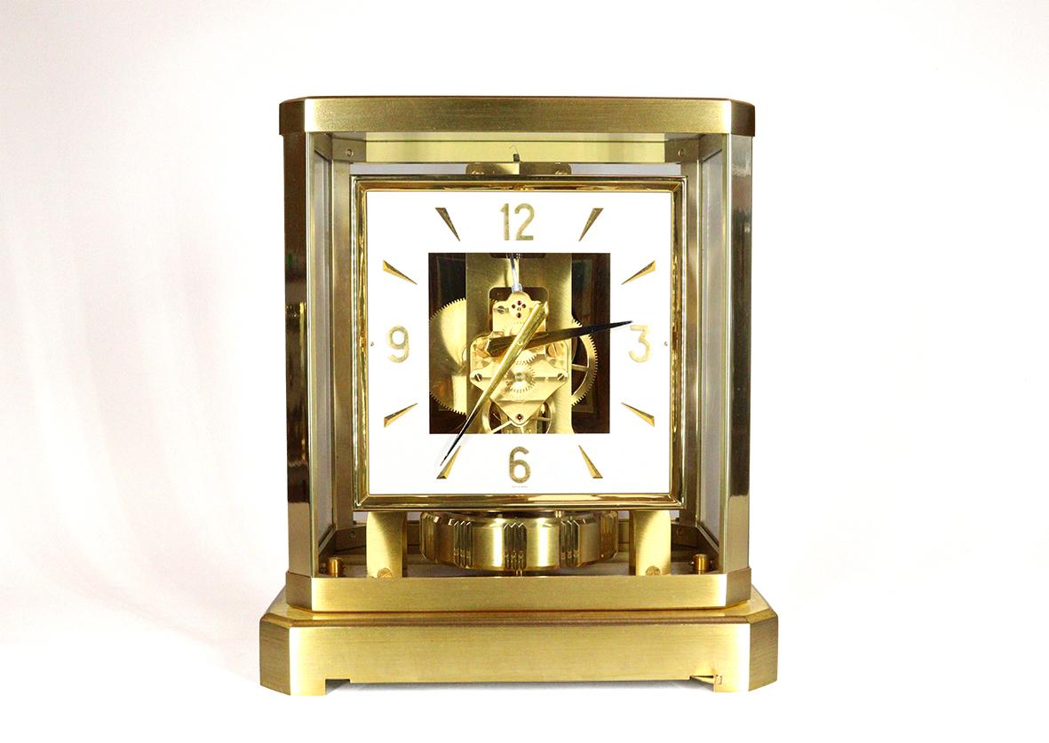Une belle pendule Atmos de Jaeger-LeCoultre numérotée 120482, avec un cadran carré à chiffres arabes et lattes dorés et des aiguilles à pointe fumée. Cette horloge a conservé son support mural doré d'origine, décoré d'une combinaison de plaques d'or