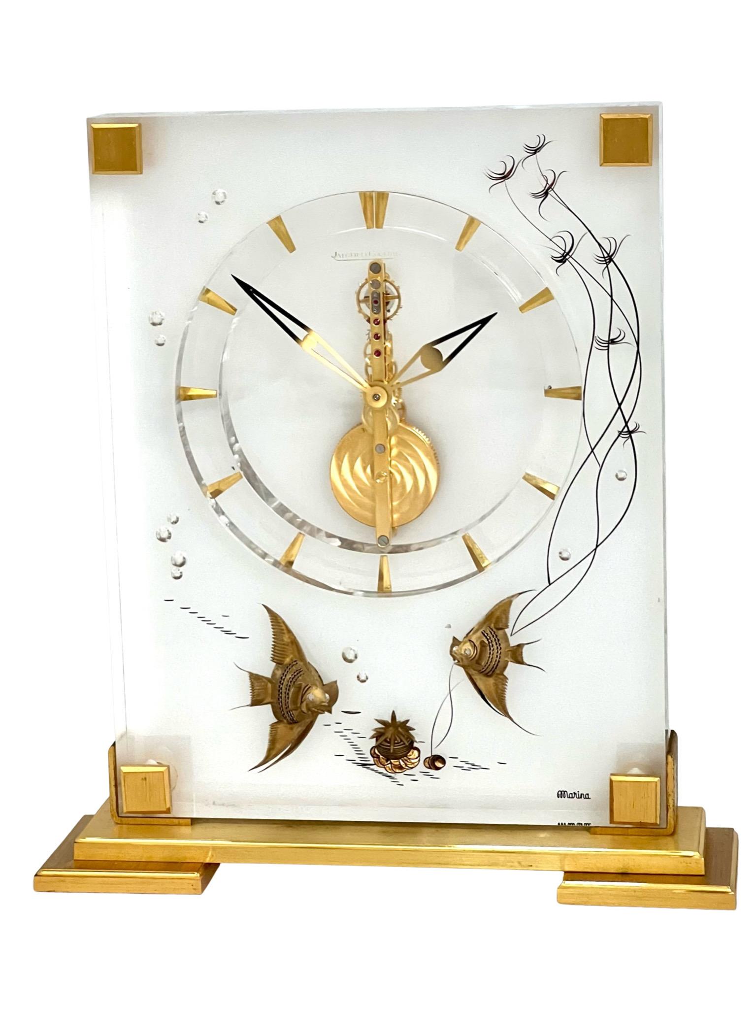 Stunning Jaeger LeCoultre mid-century marina desk clock with a Maritime theme, number 352. The clock has a polished gilt brass and lucite case. It is beautifully decorated with an underwater scene of fish and sea plants.

This delightful clock sits