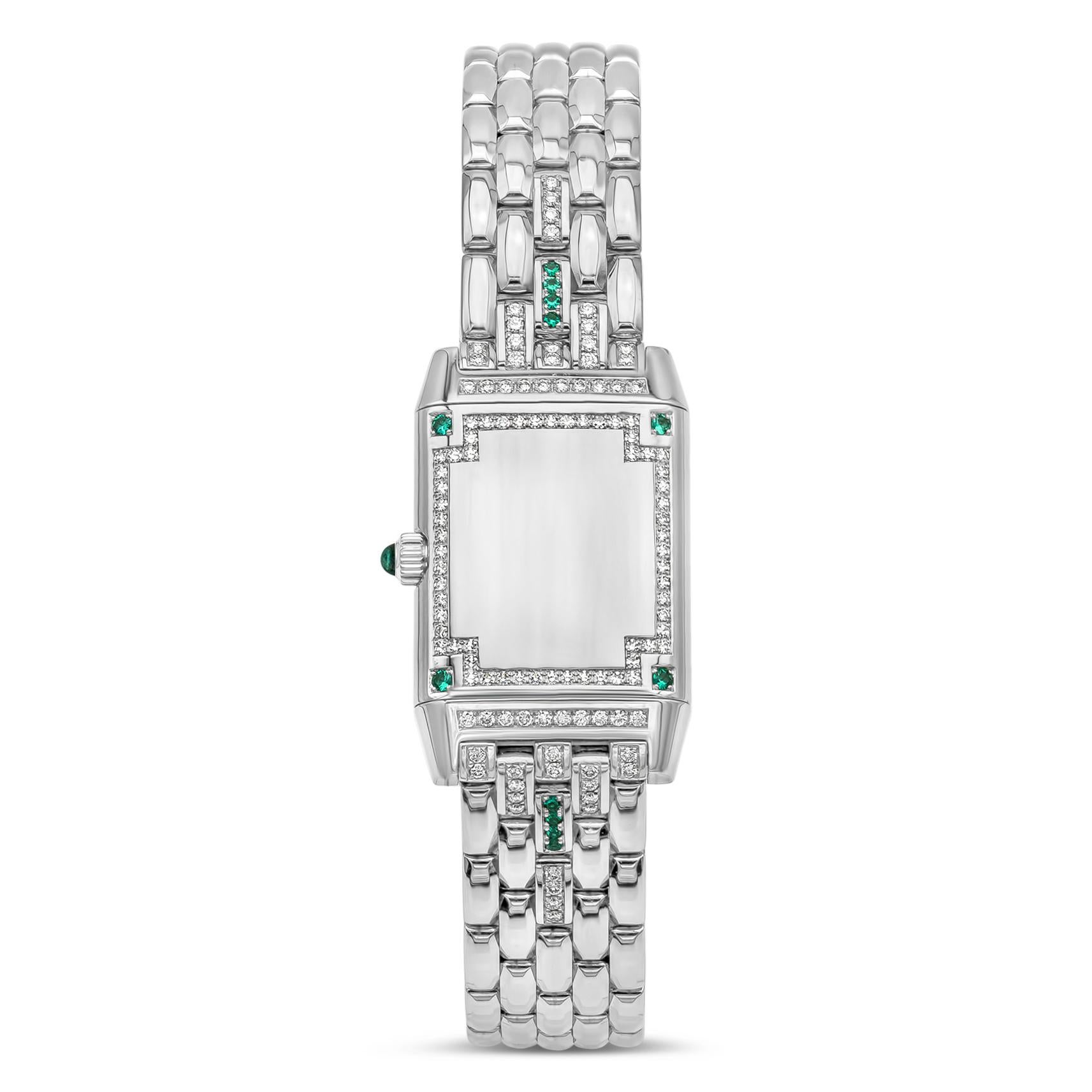 A rare and iconic Jaeger-LeCoultre Reverso.  The case features a white dial set with diamonds to mark the numbers with dauphine hour and minute hands. White gold bezel encrusted with diamonds and emeralds. Case reverses to a plain diamond encrusted