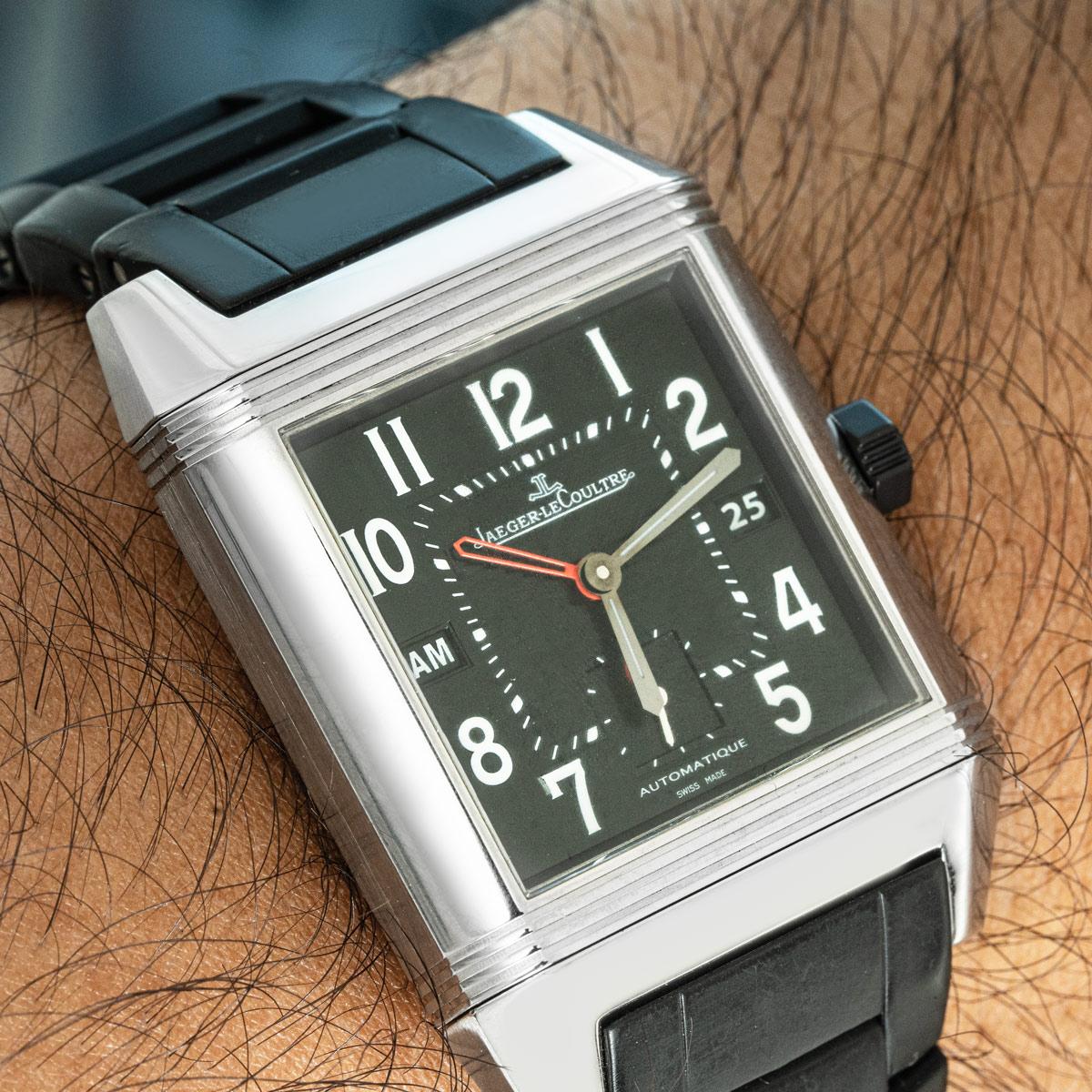 Un Reverso Squadra Hometime di Jaeger-LeCoultre in acciaio inossidabile. Quadrante nero con numeri arabi, datario a ore 3 e piccoli secondi a ore 6. Il quadrante presenta anche una lancetta per il secondo fuso orario e un indicatore giorno/notte a