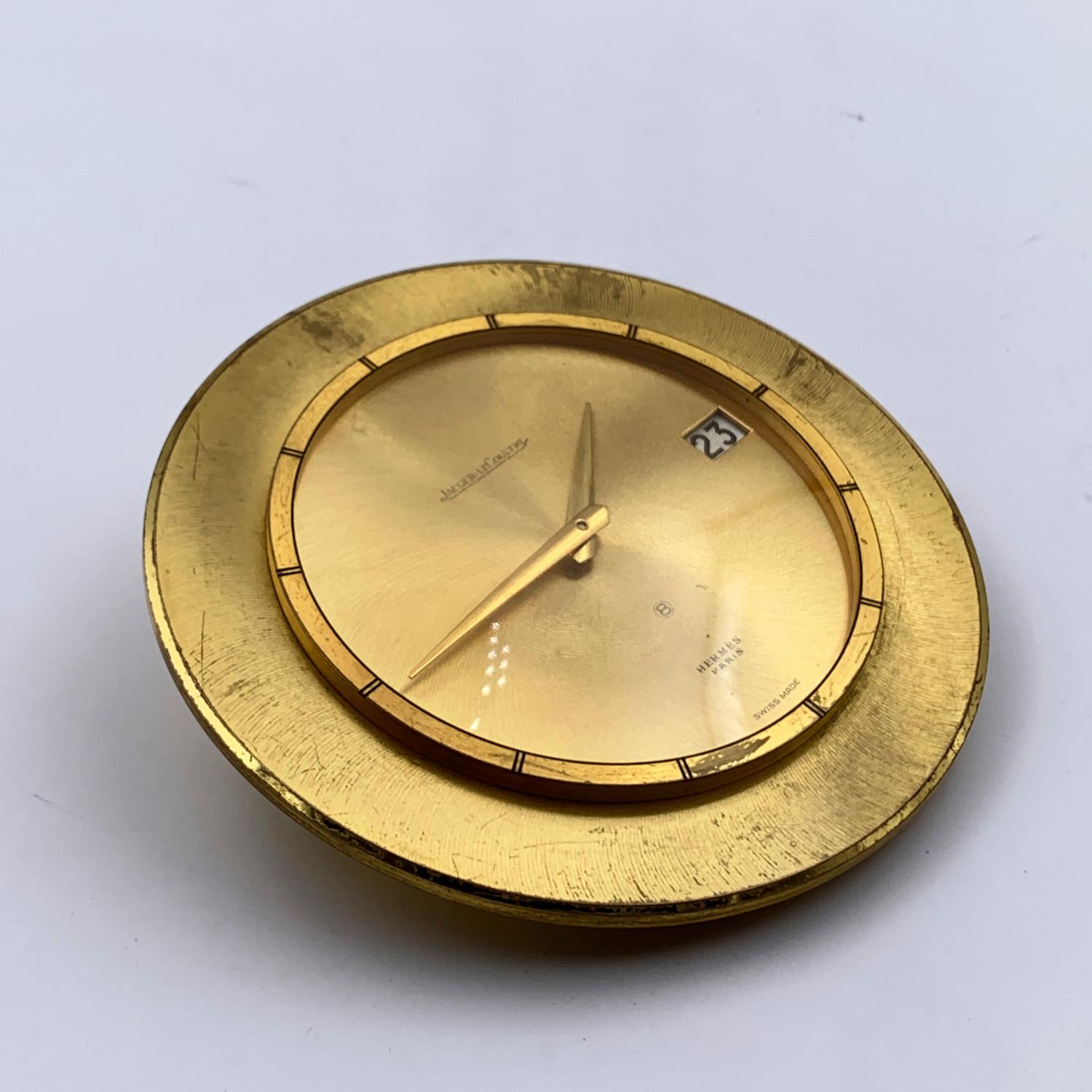 Jaeger LeCoutre for Hermes Vintage gold metal Desk Clock from the mid-century. Round-shaped. Mechanical movement- Swiss Made. Date indicator at 3. It is marked 'Hermes Paris' and 'Jaeger LeCoutre' on the dial. Diameter: 5 inches - 12.7