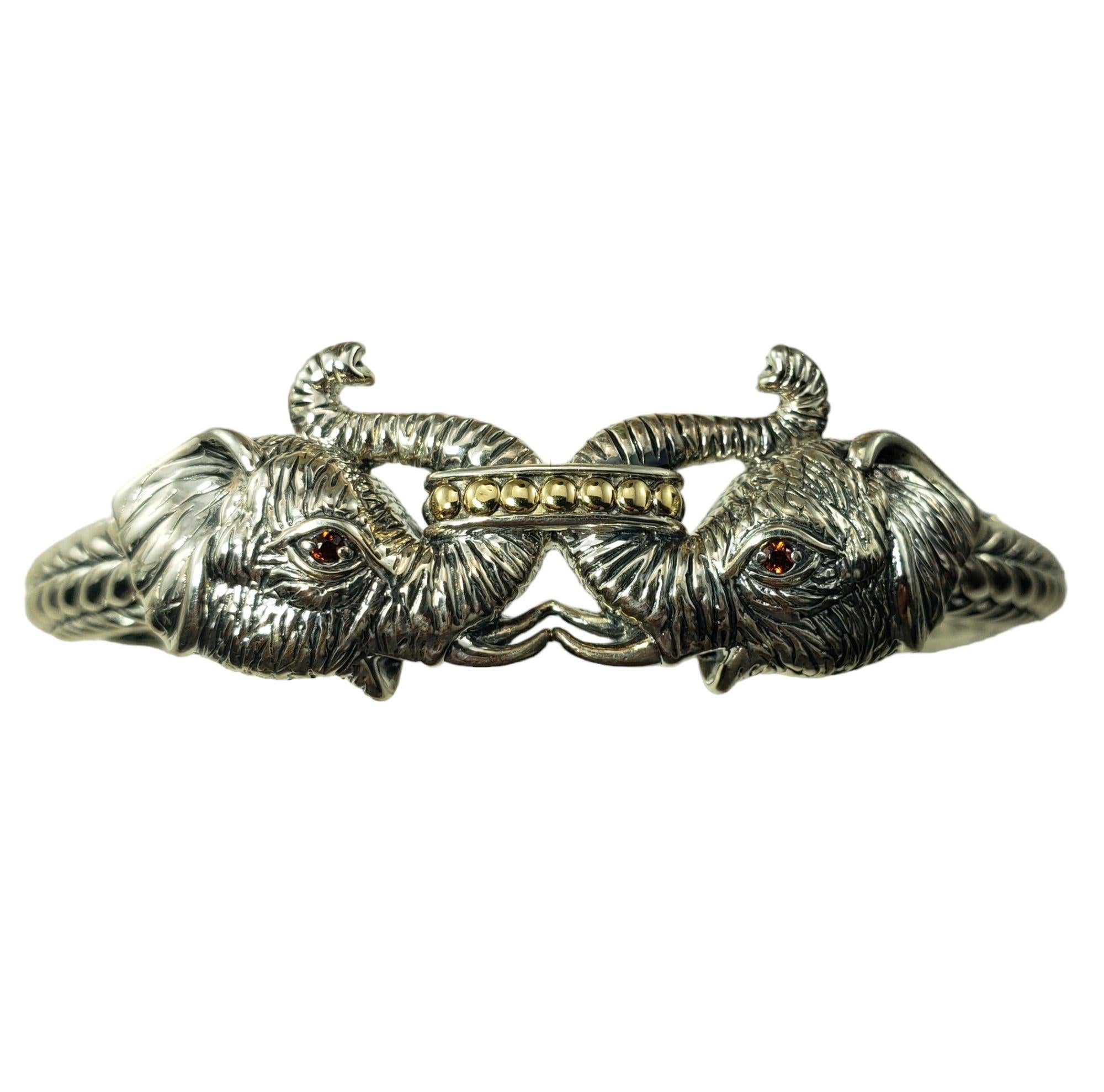 JAI by John Hardy Sterling Silber und 14 Karat Gelbgold Doppelkopf Elefant Manschettenarmband-

Dieses elegante Doppelkopf-Elefantenarmband ist mit 14-karätigem Gelbgold und zwei facettierten roten Edelsteinen verziert. Gefertigt aus detailreichem