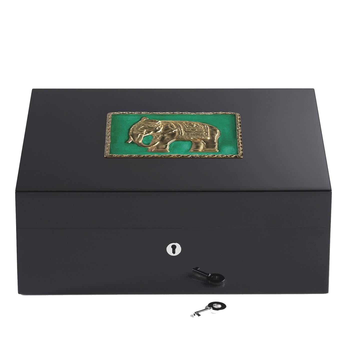 This refined humidor is an original object crafted of precious wood. Showcasing a sleek design, adorned with a symbol of the Indian culture, the elephant. The square decoration features golden edges that match the central reproduction of the