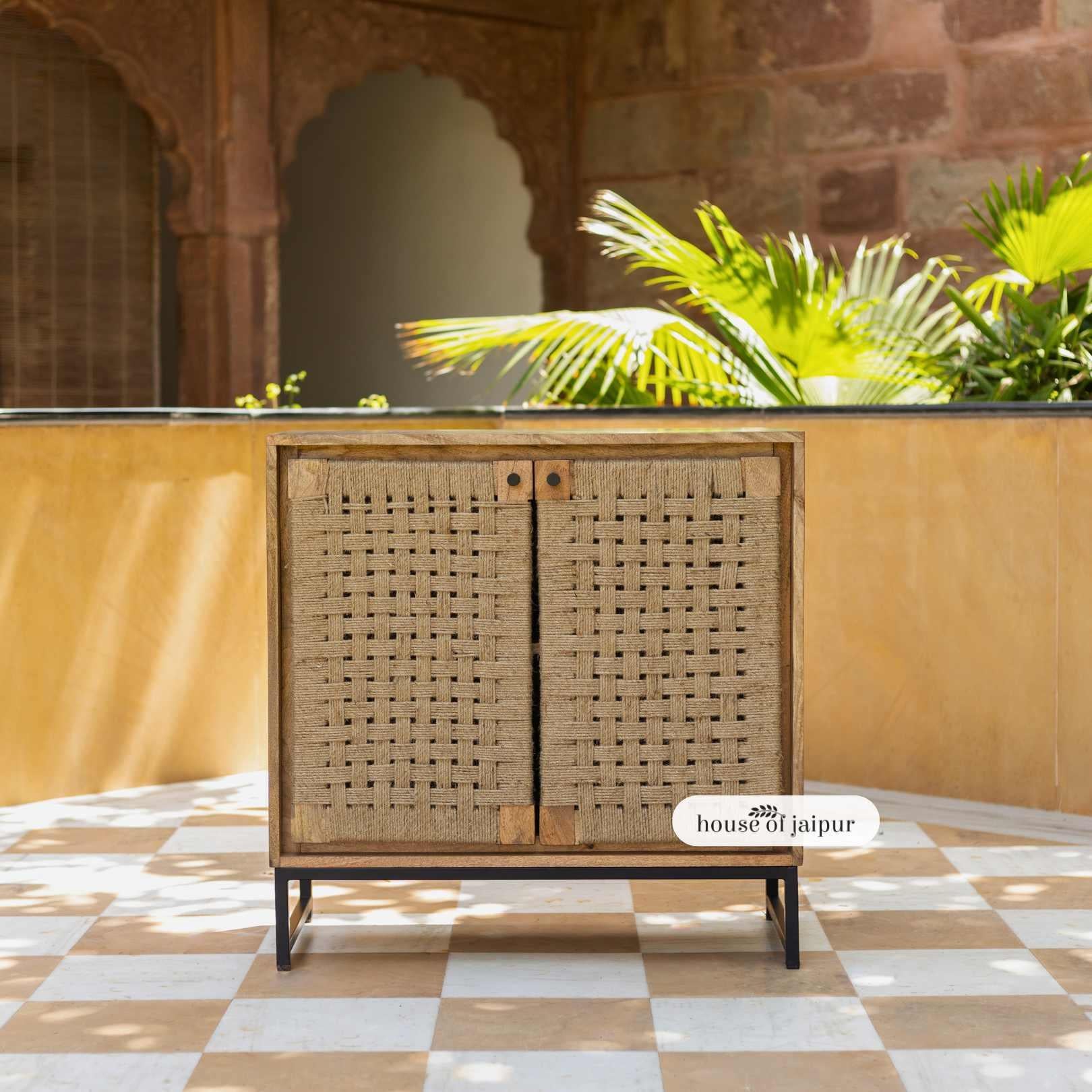 Il mobile credenza Jaipur in iuta intrecciata a mano è una graziosa miscela di artigianato, struttura e design senza tempo. Realizzato a mano in legno massiccio e appoggiato su un'elegante base in metallo nero, questo mobile presenta ante in iuta