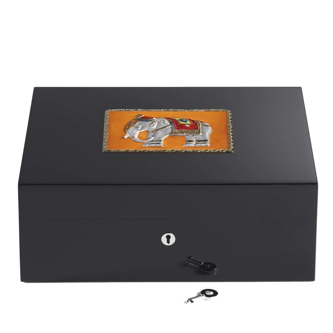 This wooden humidor is an exclusive item that can contain up to 75 cigars. It showcases an elegant and simple silhouette, which is painted black. The distinctive feature making this piece truly unique is the decoration gracing its lid that depicts