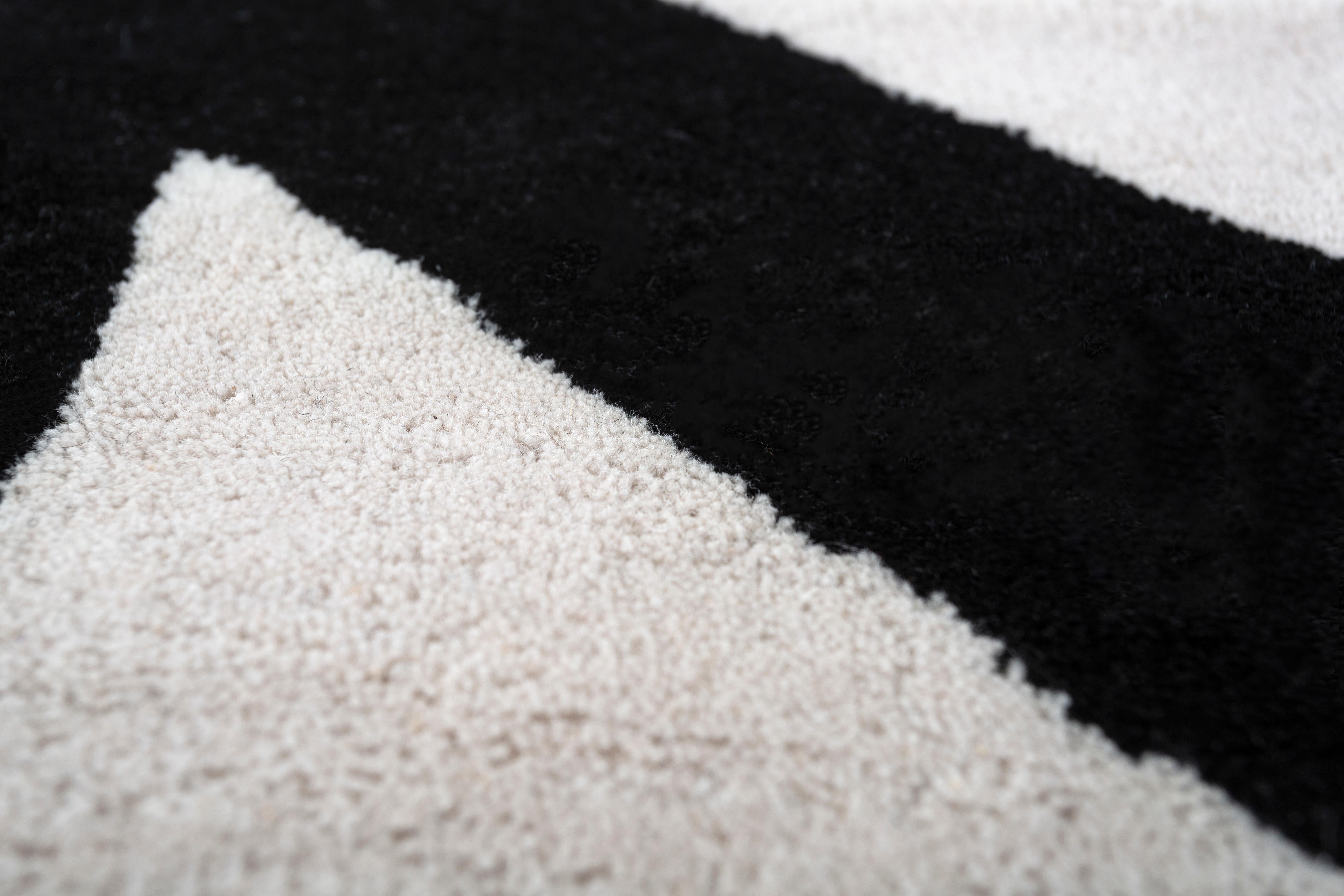 Jaipur Rugs Die Adrift Collection ist eine kühne Erkundung der Kontraste, bei der auffällige Schwarz-Weiß-Muster die Grundlage für jedes Stück bilden. Diese monochromen Elemente sorgen für eine starke, zeitlose Aussage, während kräftige Farbtupfer