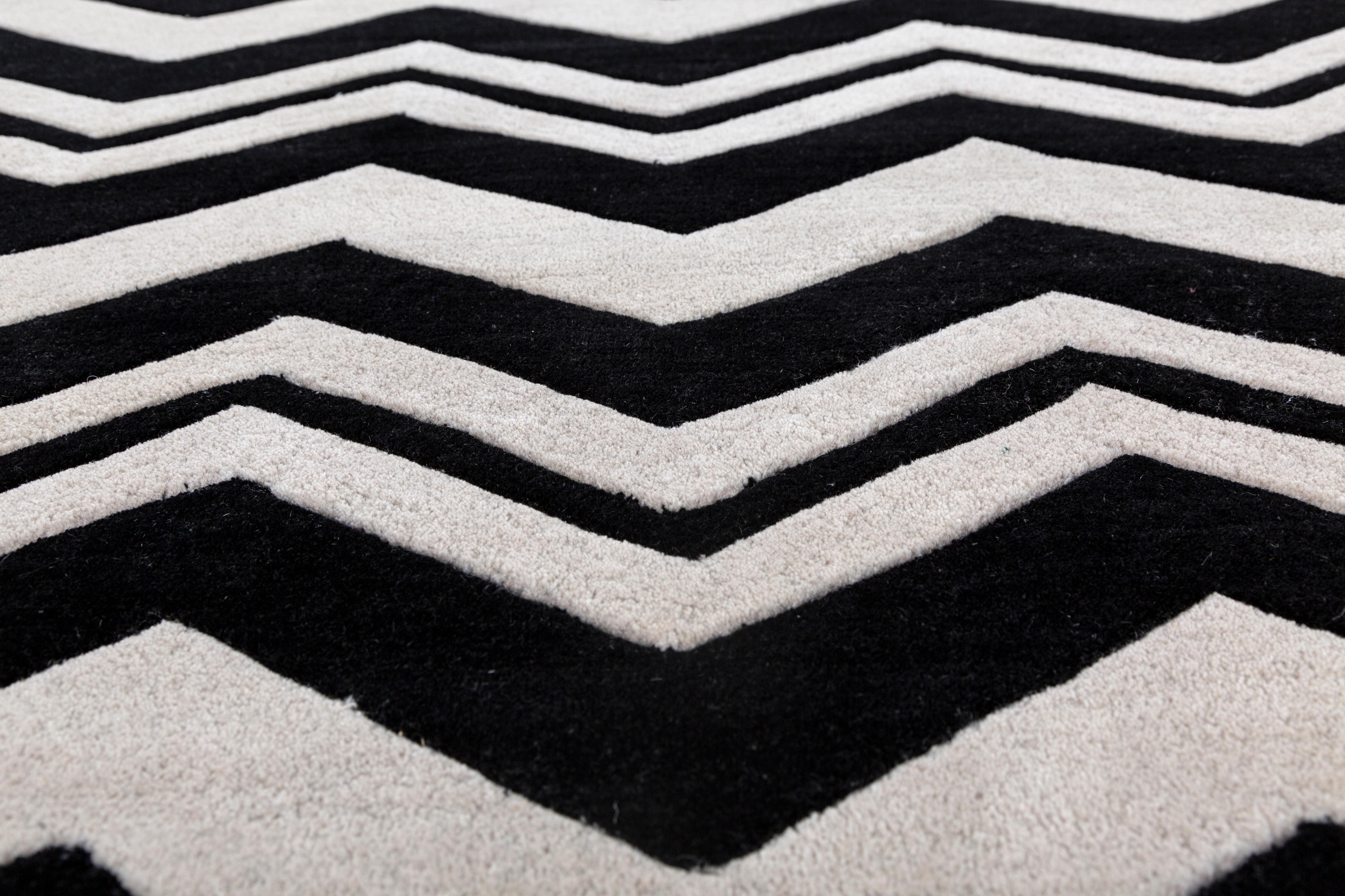 Jaipur Rugs Die Adrift Collection ist eine kühne Erkundung der Kontraste, bei der auffällige Schwarz-Weiß-Muster die Grundlage für jedes Stück bilden. Diese monochromen Elemente sorgen für eine starke, zeitlose Aussage, während kräftige Farbtupfer
