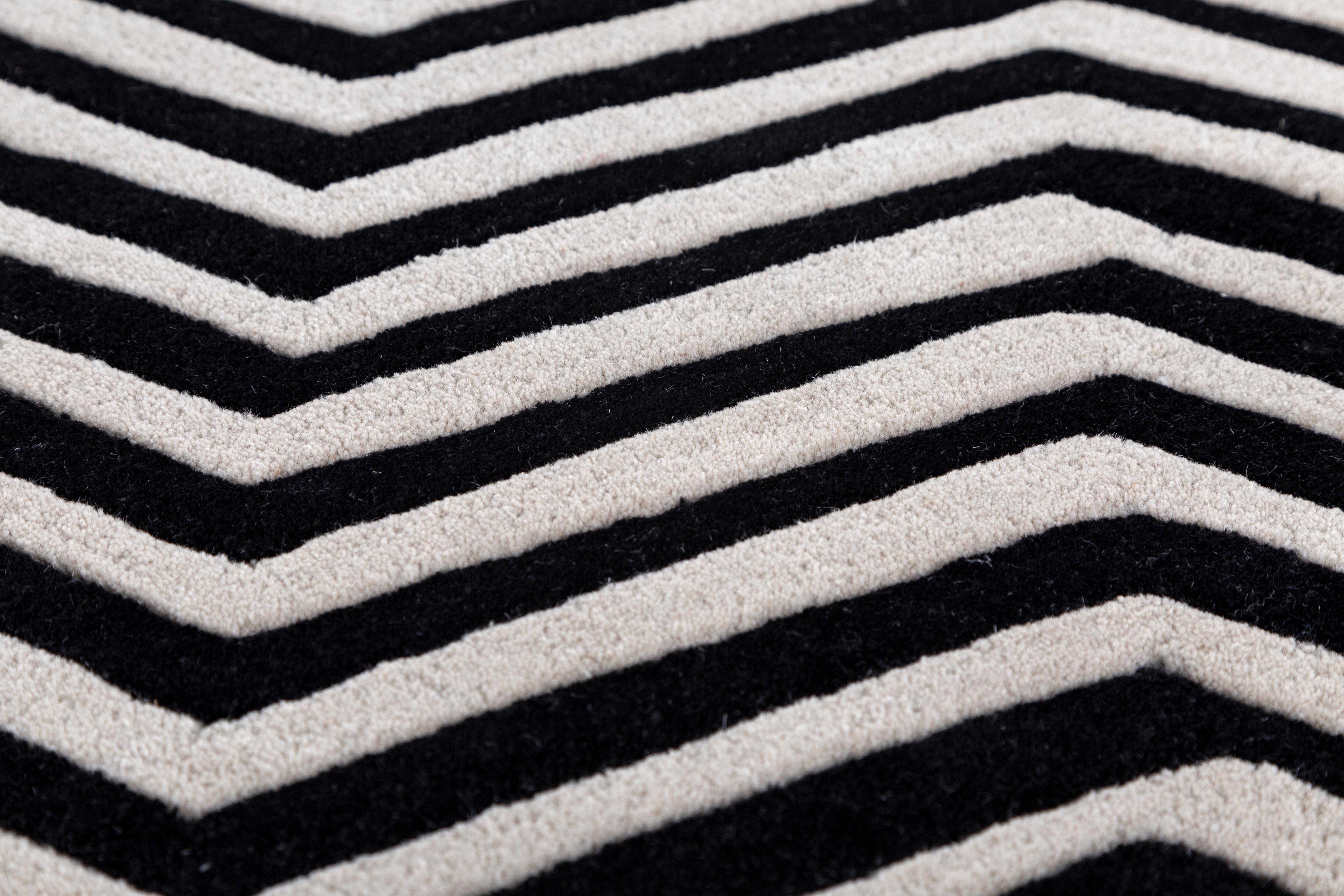 Jaipur Rugs Die Adrift Collection ist eine kühne Erkundung der Kontraste, bei der auffällige Schwarz-Weiß-Muster die Grundlage für jedes Stück bilden. Diese monochromen Elemente sorgen für eine starke, zeitlose Aussage, während kräftige Farbtupfer