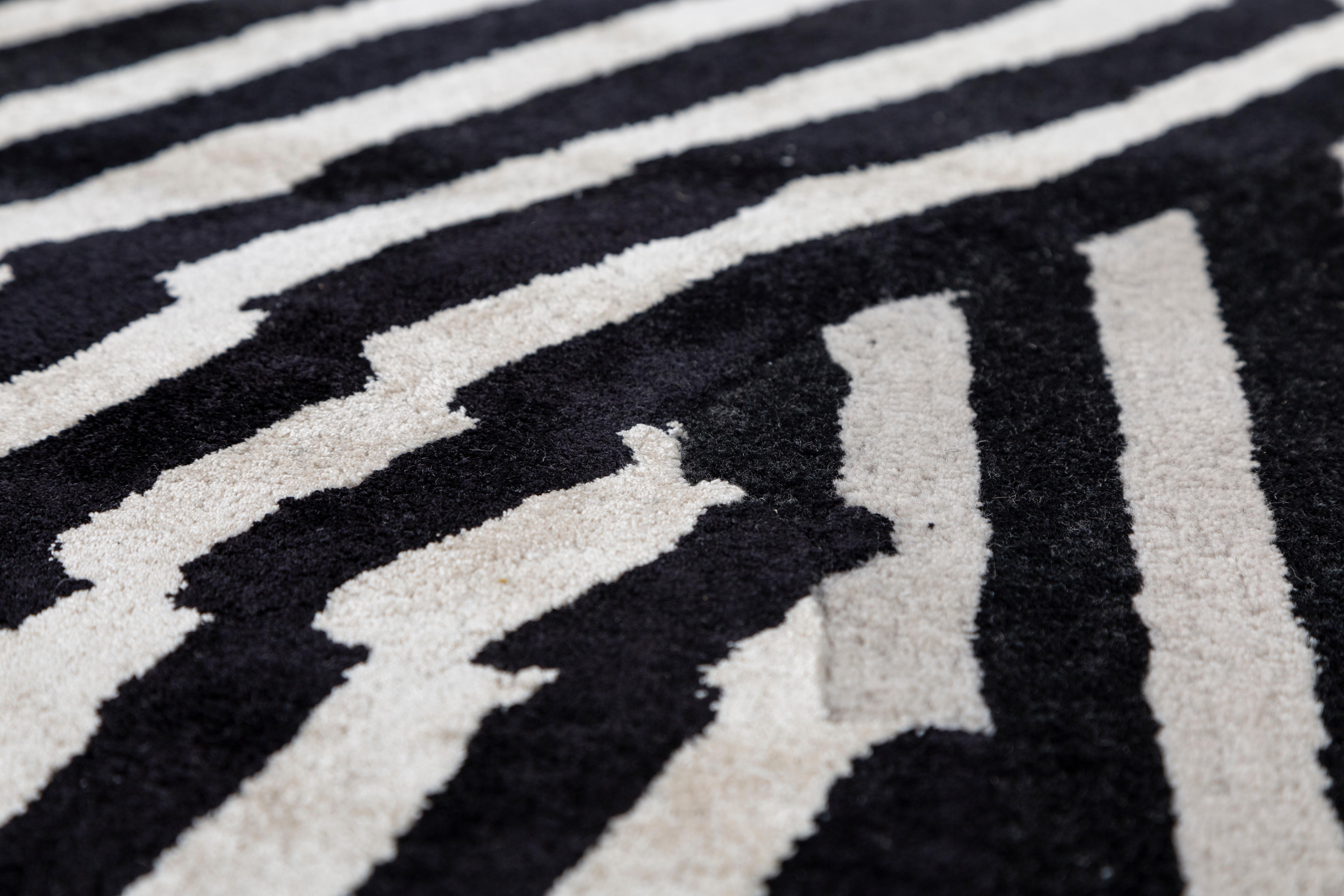Jaipur Rugs Die Adrift Collection ist eine kühne Erkundung der Kontraste, bei der auffällige Schwarz-Weiß-Muster die Grundlage für jedes Stück bilden. Diese monochromen Elemente sorgen für eine starke, zeitlose Aussage, während kräftige Farbtupfer