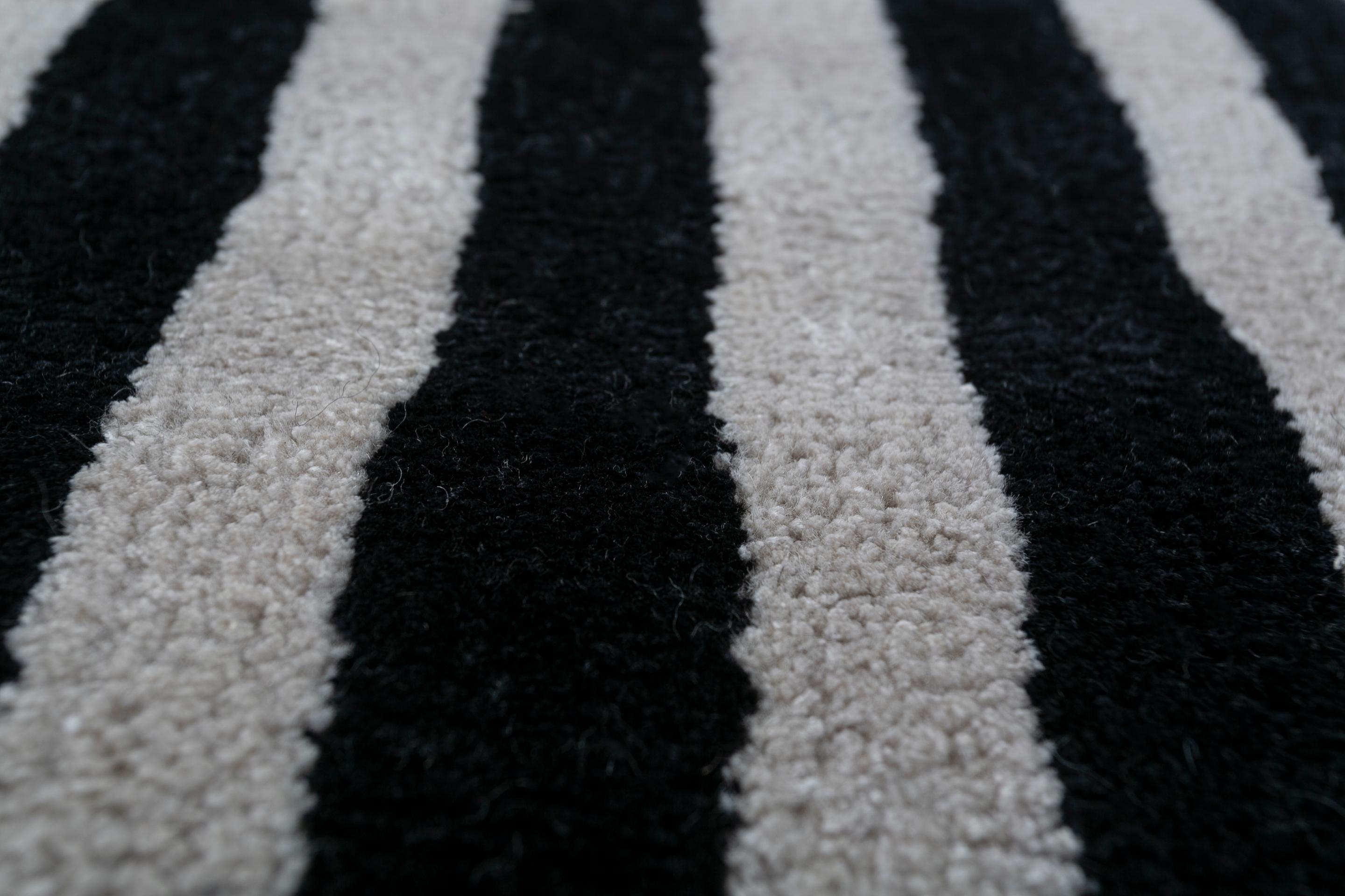 Jaipur Rugs Die Adrift Collection ist eine kühne Erkundung der Kontraste, bei der auffällige Schwarz-Weiß-Muster die Grundlage für jedes Stück bilden. Diese monochromen Elemente sorgen für eine starke, zeitlose Aussage, während kräftige Farbtupfer