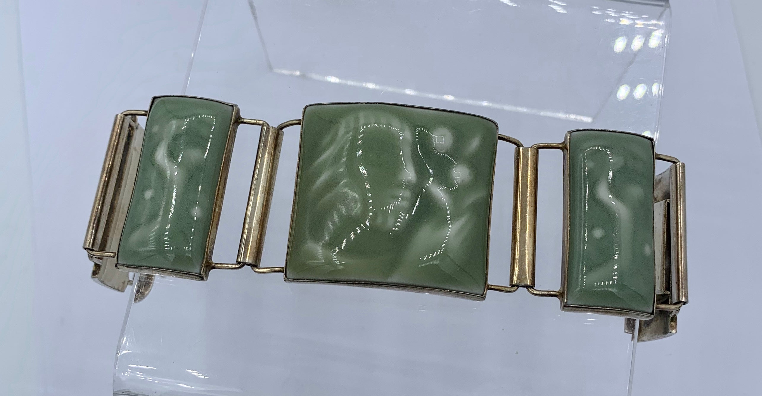 Royal Copenhagen Porcelain celedon green glaze panels by Jais Nielsen depicting a man with a flower bouquet and a kneeling woman are set in Sterling Silver in this extraordinary Mid-Century Modern Bracelet made by A. Dragsted of Denmark.  The