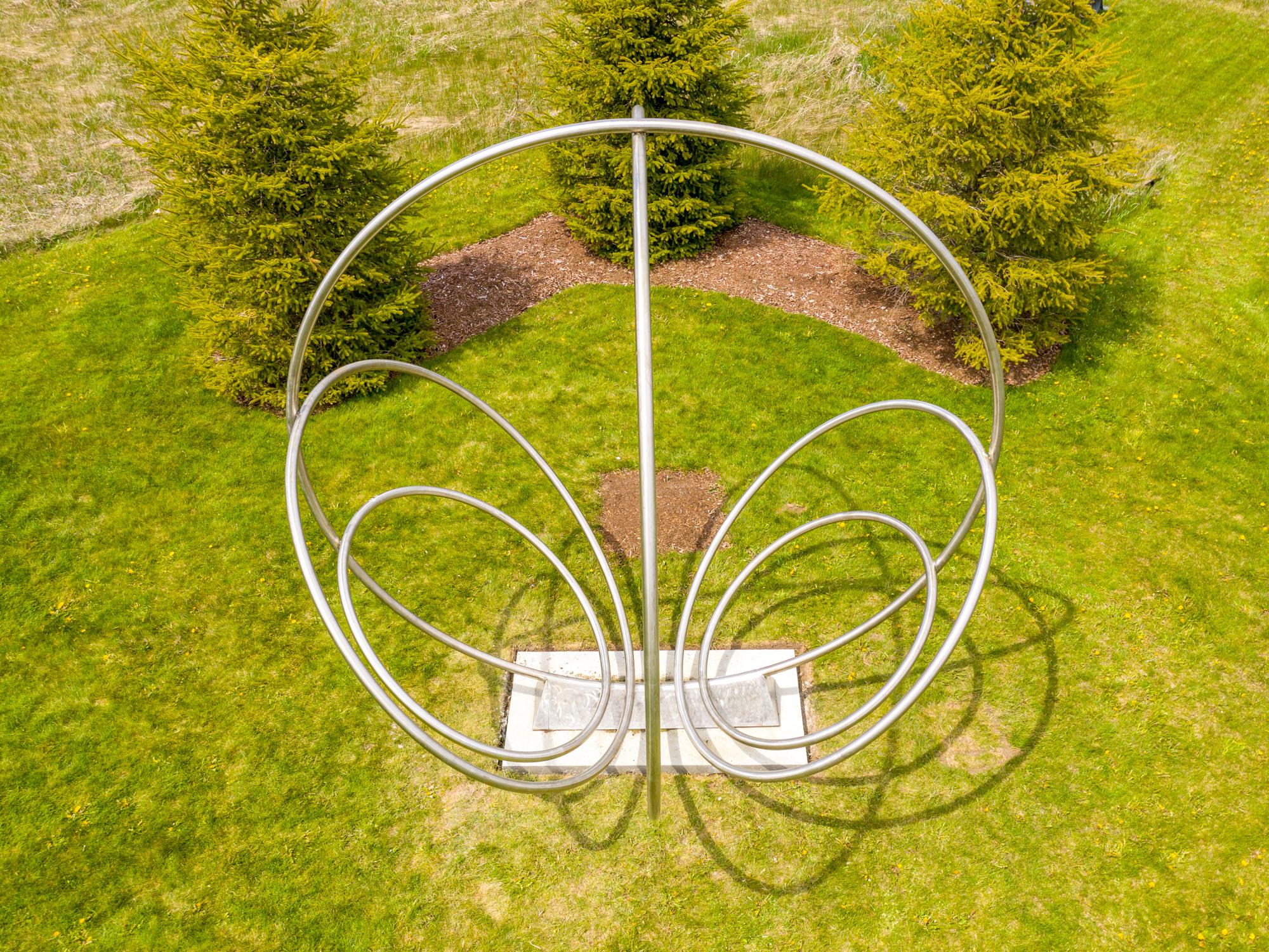 Canadian artist Jake Goertzen creates a symmetrical design with six stainless steel rings in this elegant outdoor sculpture. 

