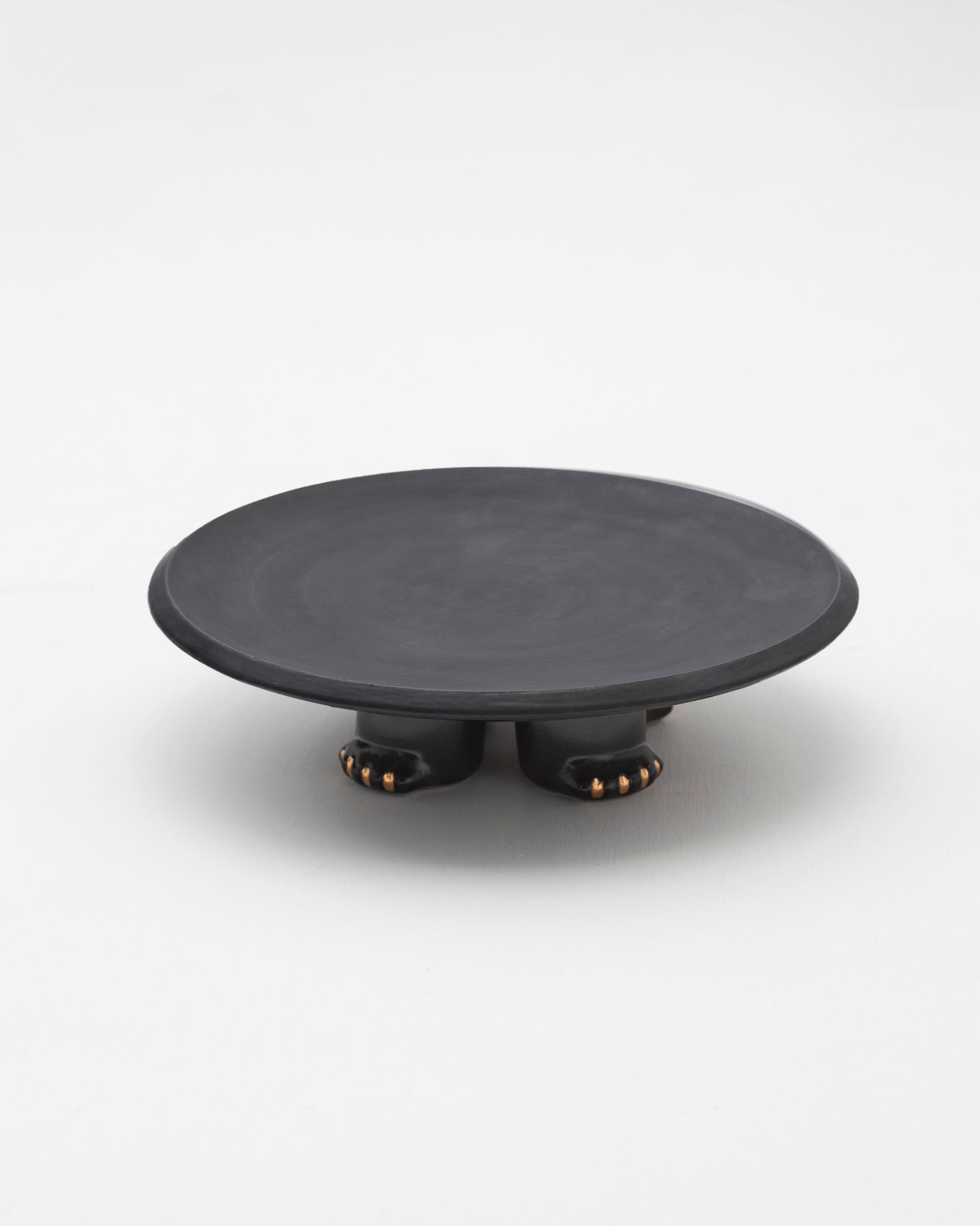 Plato decorativo de cerámica moldeada en barbotina, acabado con un rico esmalte negro o verde oscuro, realzado con detalles de brillo dorado.

Inspirado en Jama-Coaque (350 a.C.-1532 d.C.), un incensario o mesa circular que combina representaciones