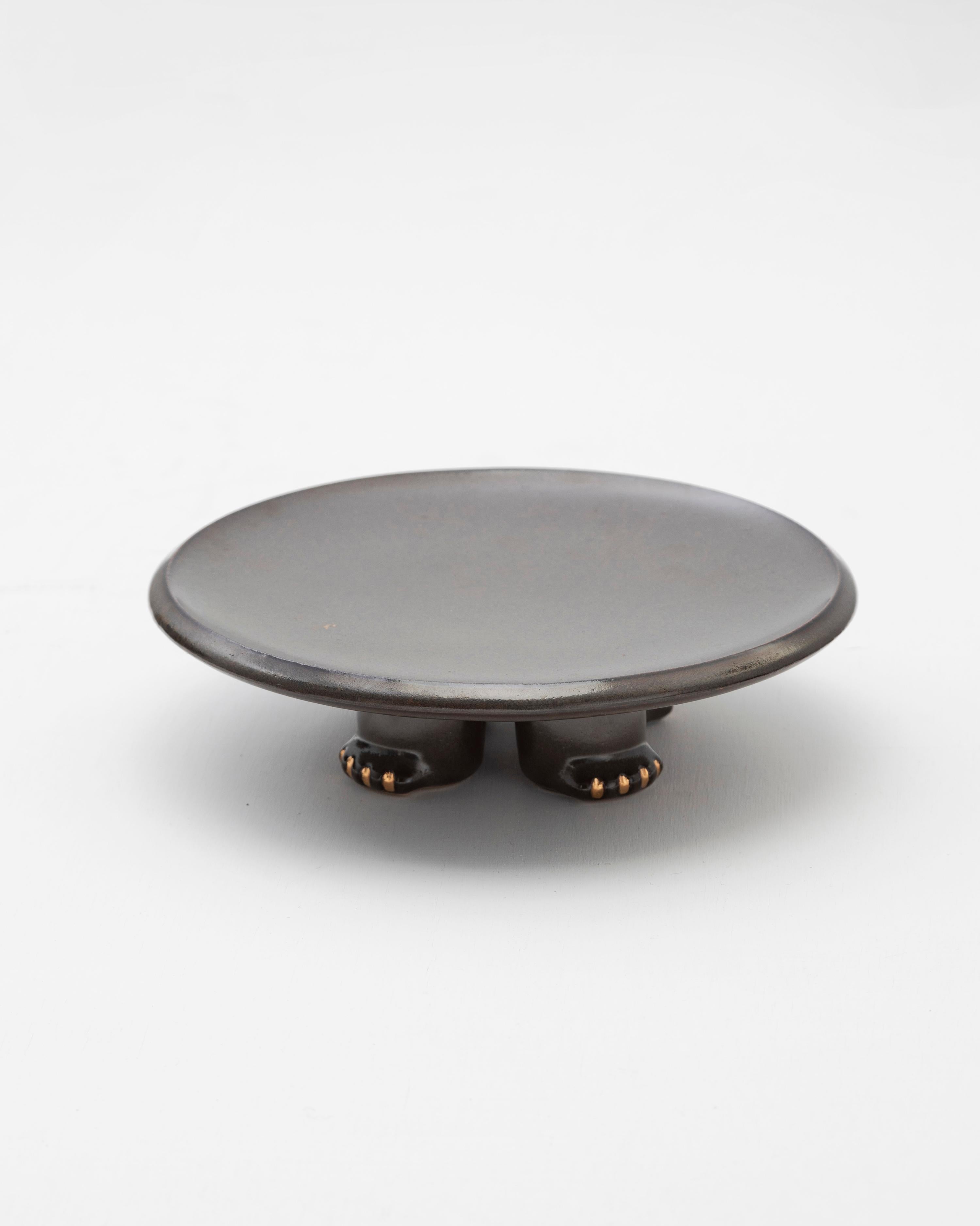 Plat décoratif en céramique coulée à la barbotine, recouvert d'une riche glaçure noire ou vert foncé, rehaussée de détails dorés.

Inspiré du Jama-Coaque (350 av. J.-C. - 1532 ADS), un encensoir ou table circulaire qui combine des représentations