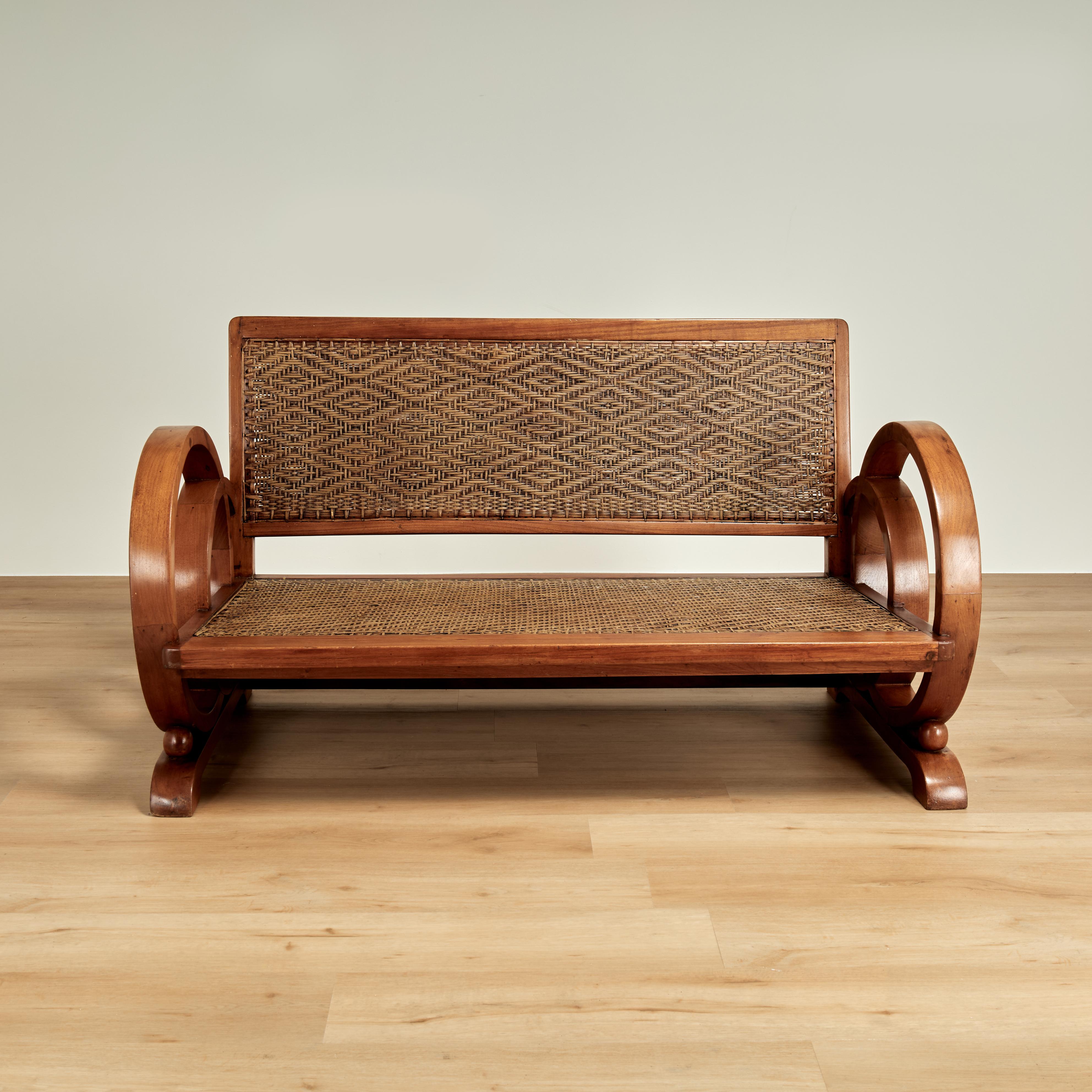 Impresionante canapé art déco jamaicano de los años 30, fabricado en caoba, con espectaculares laterales de doble círculo y respaldo y asiento de caña tejida a mano con insólitos diseños geométricos.