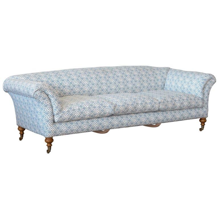 A reproduction Howard & Sons sofa, based on an early model and upholstered in reproduction Howard & Sons ticking, with traditional sack back upholstery, turned oak legs and stamped brass casters. Client’s own material, c.22m of plain fabric