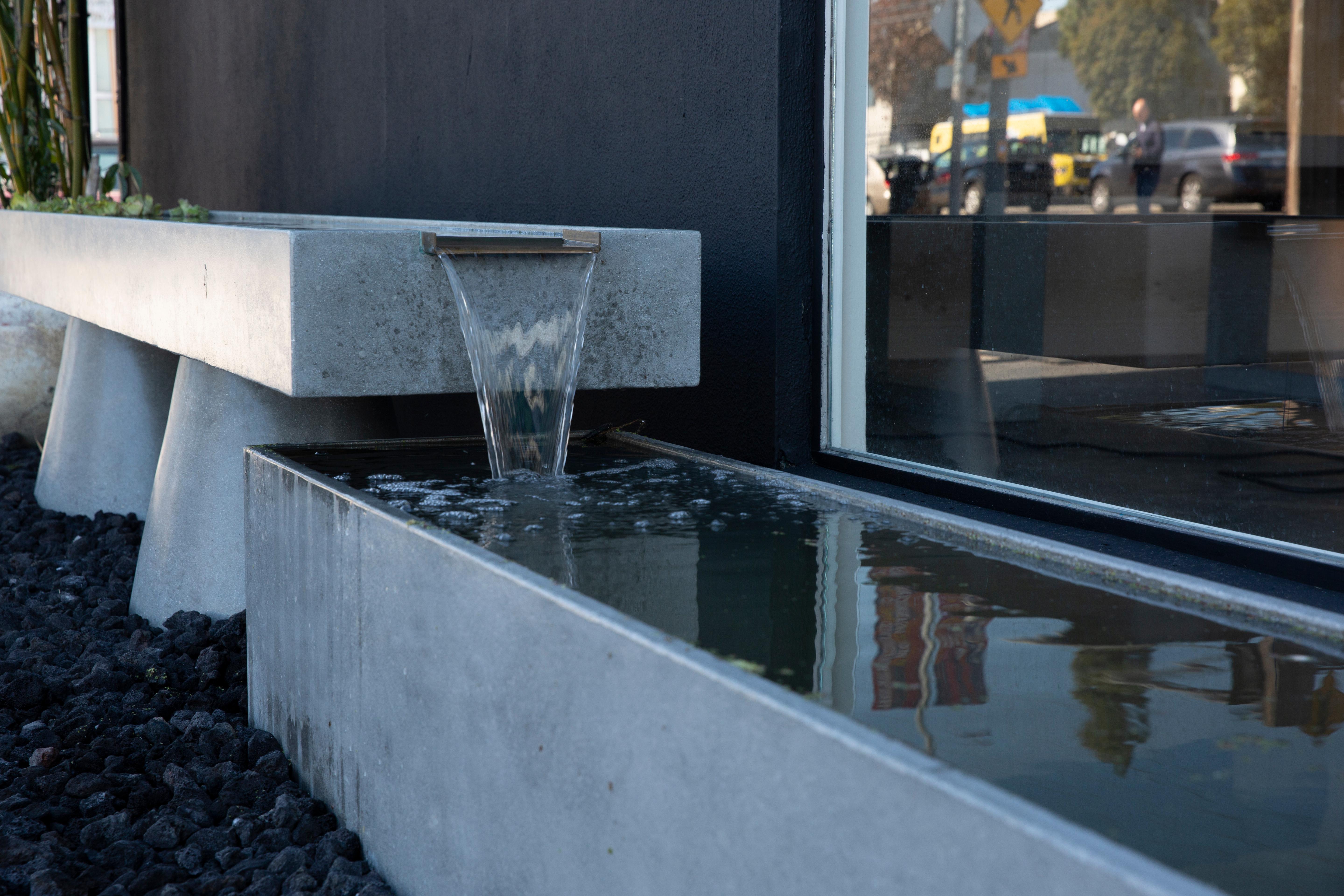 James de Wulf's two-tier concrete fountain boasts simplistic beauty with a smooth polished concrete surface, accented with a bronze waterfall. The beauty of bronze, ductile and resistant to corrosion, married with the strength and density of