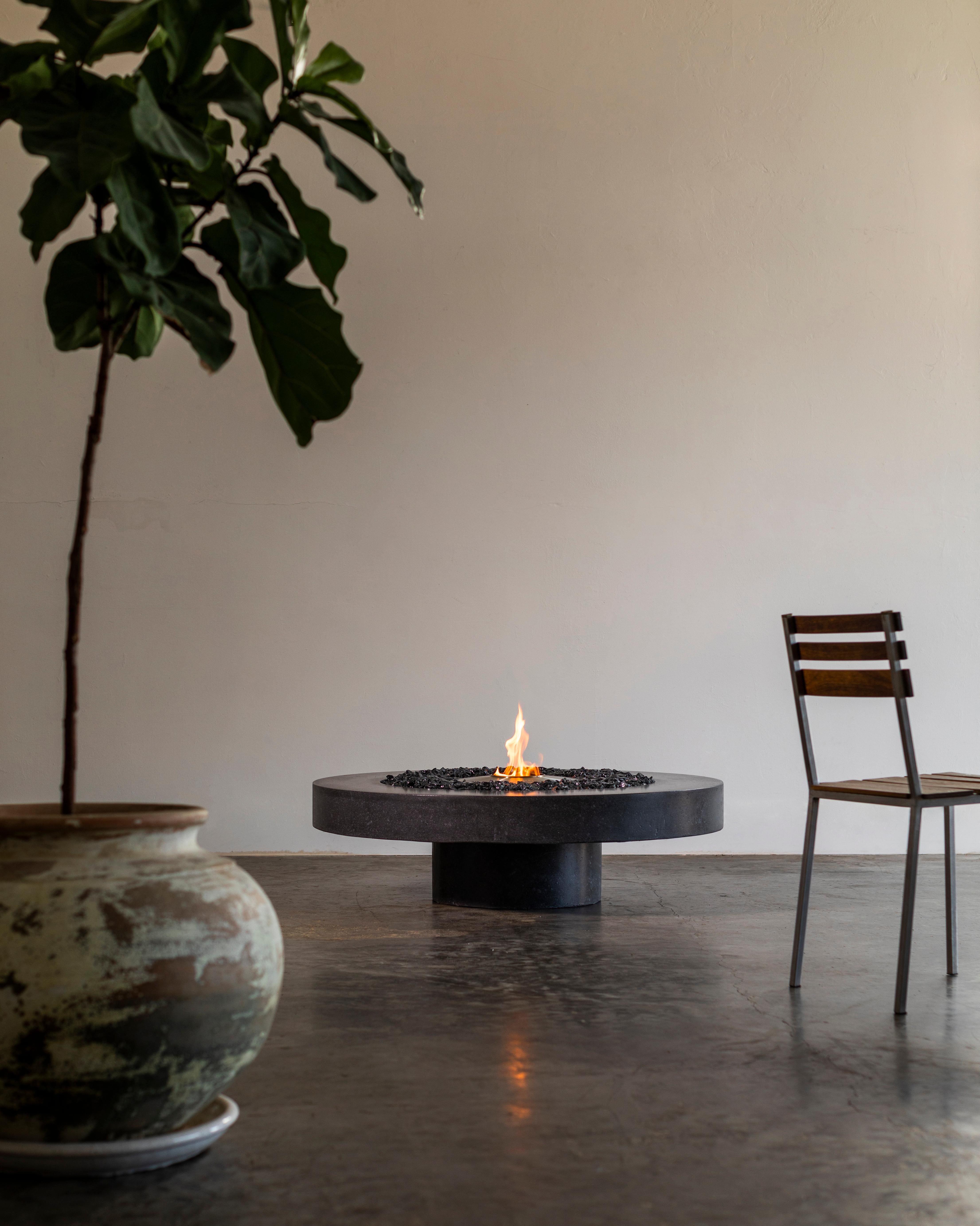 James de Wulf's Floating Concrete Fire Table is the first in a series of three designs. Distinctive single pedestal design creates the illusion of a floating concrete disc from seated guests and standing angles. Table is polished and sealed for a