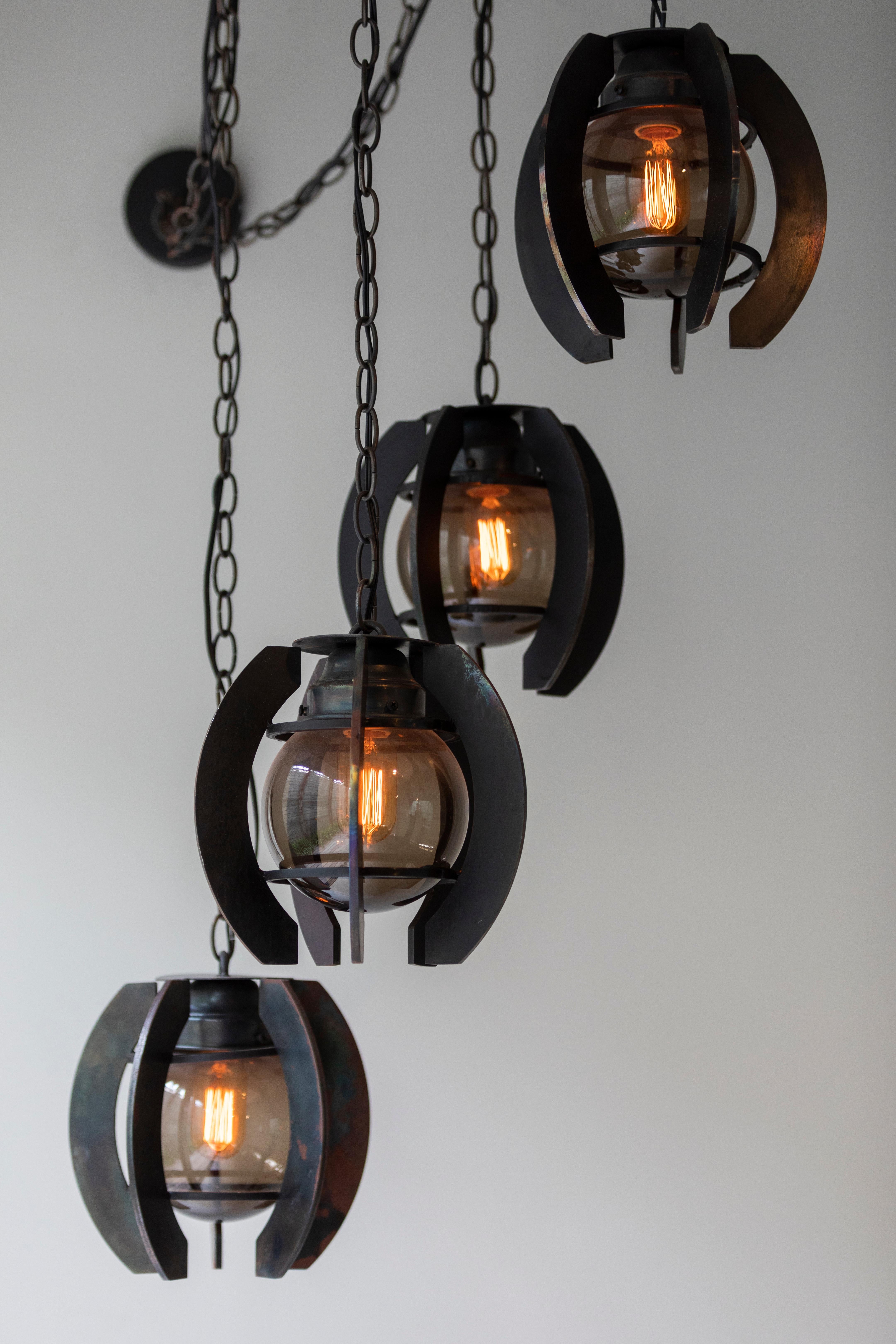 Industrial style chandelier with steel that is burnt black in a forge. Inspired by underwater mines. Comes on burnt black chain, matching canopy and 60 watt Edison style bulb. UL listed. 100% made in Los Angeles.

Set includes four Orb pendants
