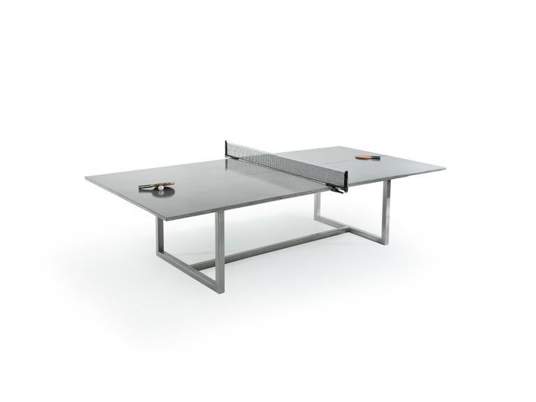 Contemporary concrete ping pong table with carbon fiber reinforcement and brushed stainless steel base. Regulation size with acid stained center line. Removable net and play accessories included. Game table doubles as a dining table. Compliment with