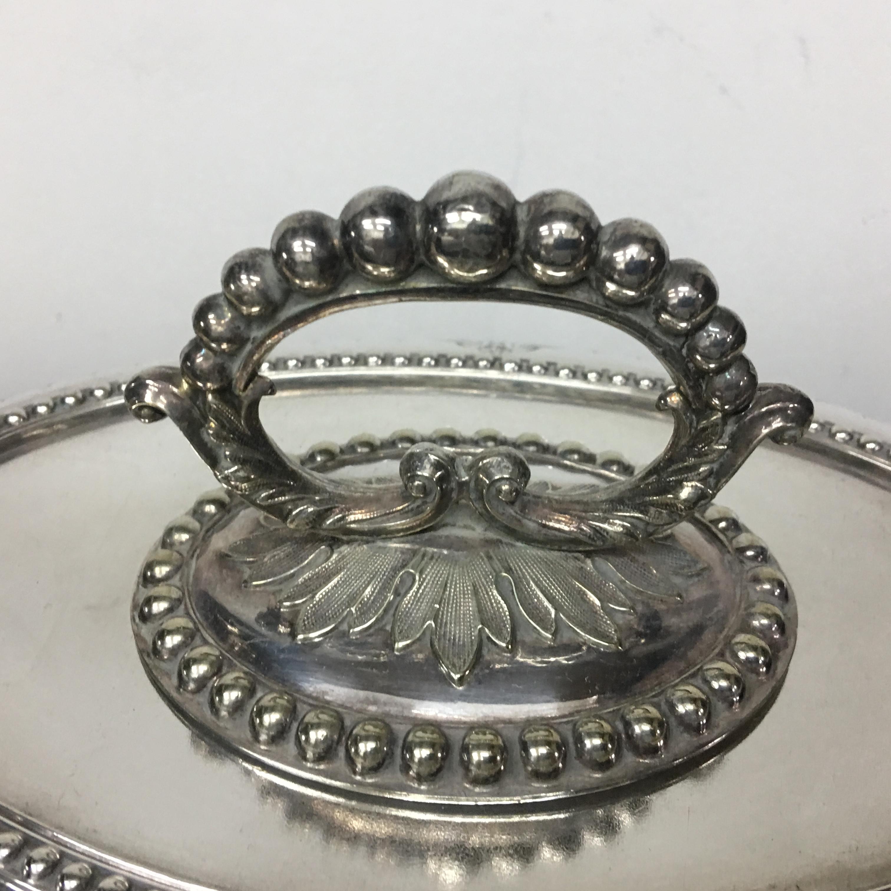 Particular English silver plated entree dish. It is composed of two distinct pieces: the lower part serves as a container for hot water and dish to keep food warm, while the upper part is shaped like a lid to cover everything.
The beaded border is