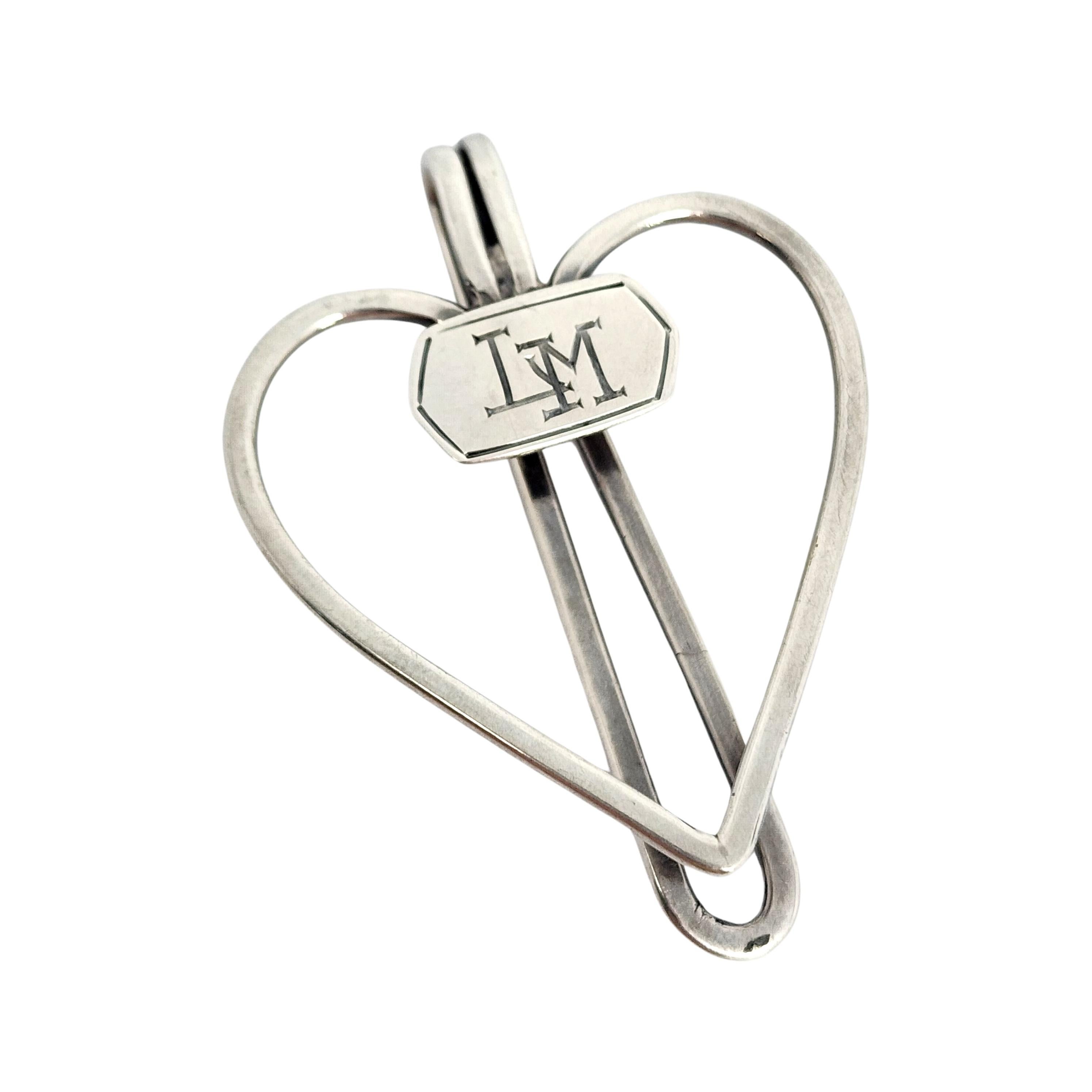 Sterling silver napkin clip by James E Blake, with monogram.

Monogram appears to be LM.

This napkin clip features an open heart design with a monogram at the center.

Measures approx 2 1/4
