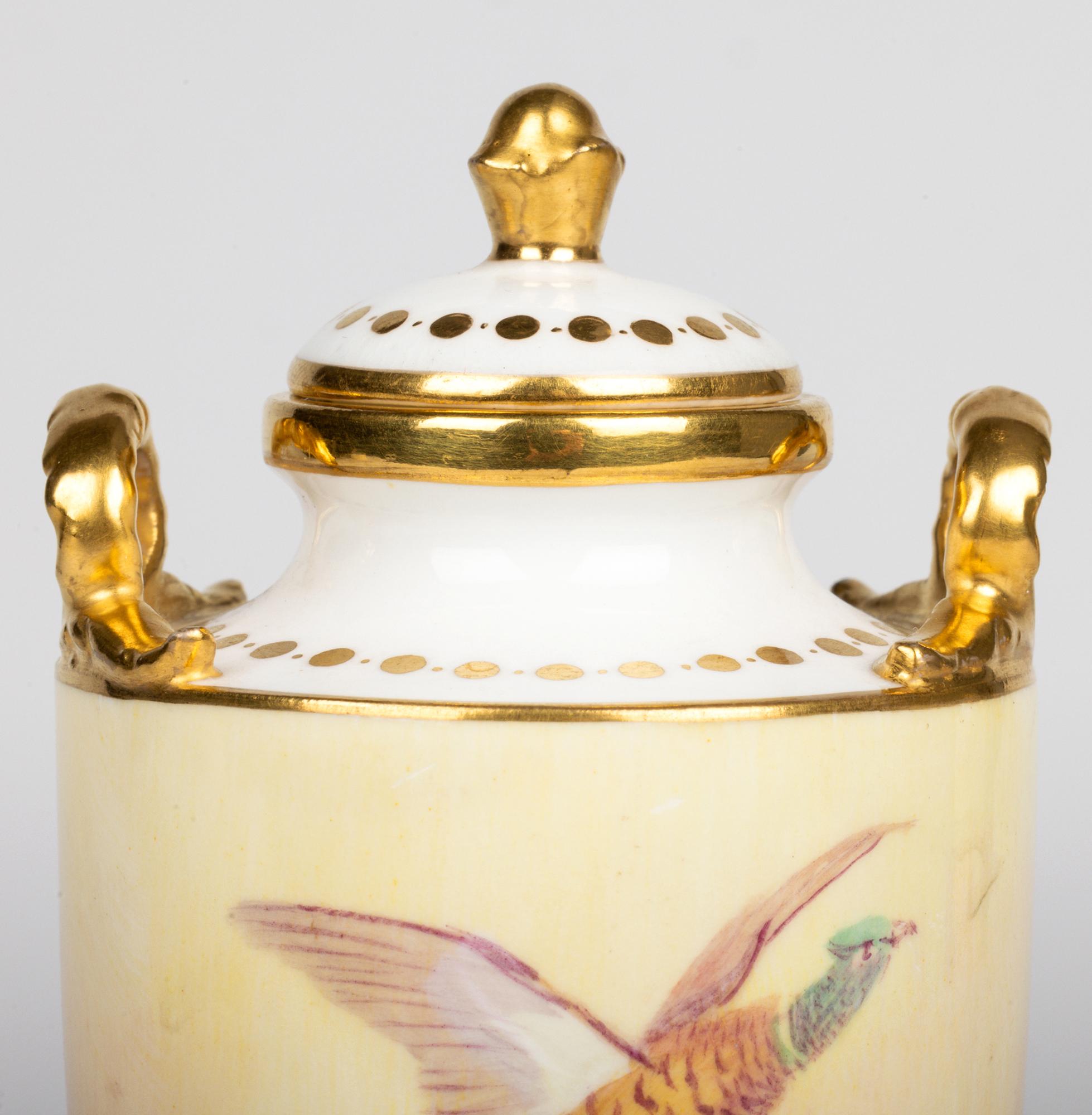 A stunning antique pair Minton twin handled lidded vases hand painted with pheasants in flight by renowned painter James Edwin Dean (1863-1935) and dating from the latter 19th century. The finely made porcelain pedestal vases are of tall slender