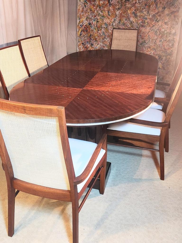 Magnifique table de salle à manger de style Art déco, commandée au milieu des années 1980 par le Studio new-yorkais de James Evanson.
Le plateau de la table est découpé en quarts dans des placages opposés d'acajou africain.
Le bord est décoré d'une