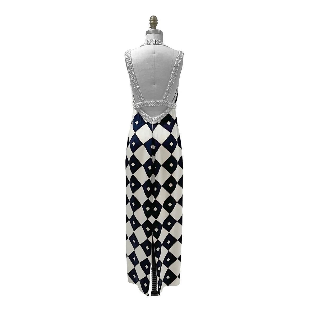 James Galanos Halterneck Gown 
Vintage 
Circa late 1980's or early 1990's 
White and Navy Blue 
Geometric diamond pattern 
Column style gown
Halter style neckline 
Bust and straps have white and crystal beaded embellishment
V neckline 
Open back
