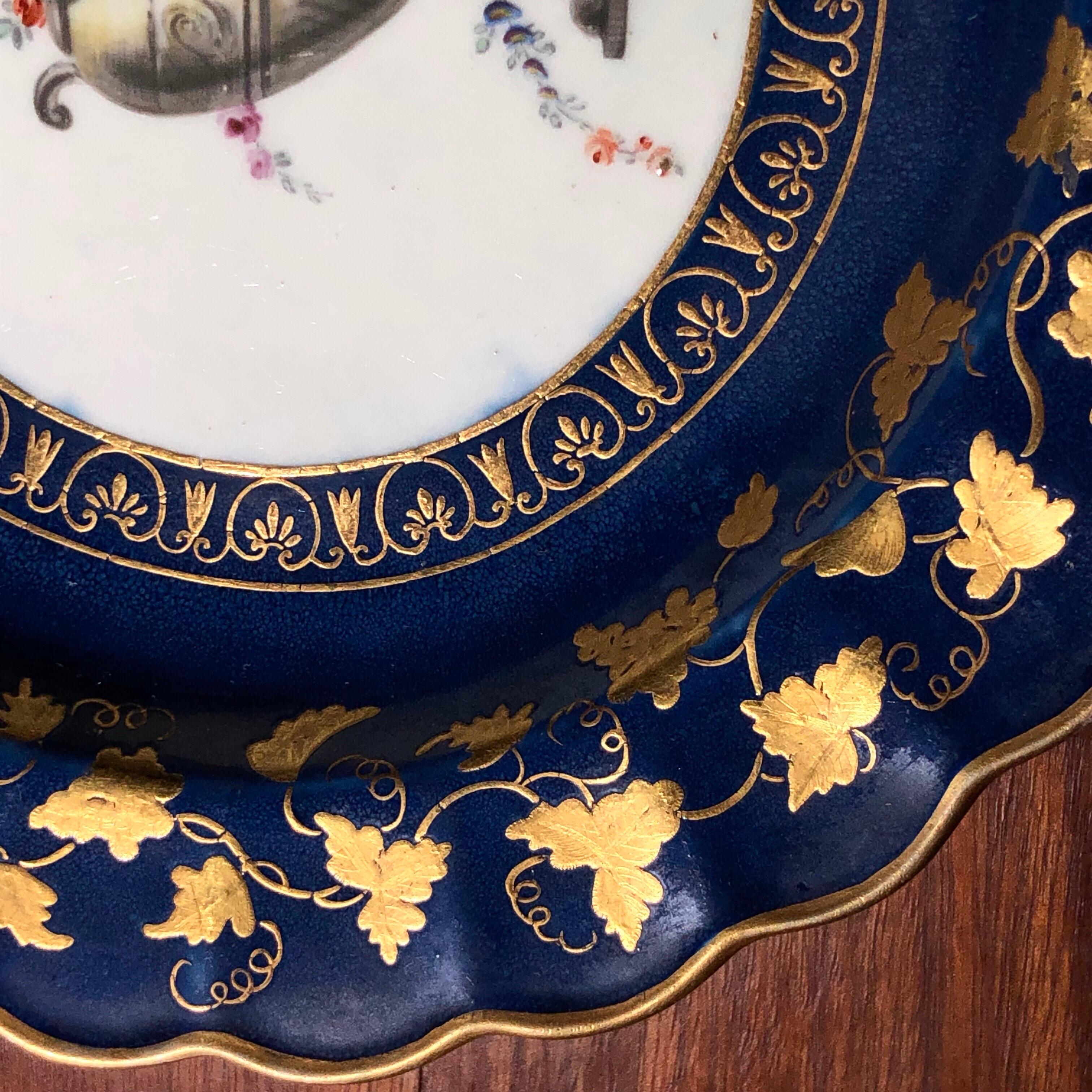 Assiette de Worcester, décorée dans le Studio Giles d'une urne classique en pierre drapée de guirlandes de fleurs colorées, le bord à fond bleu poudre avec une épaisse dorure ciselée de palmettes et de campanules en guise de bordure intérieure,