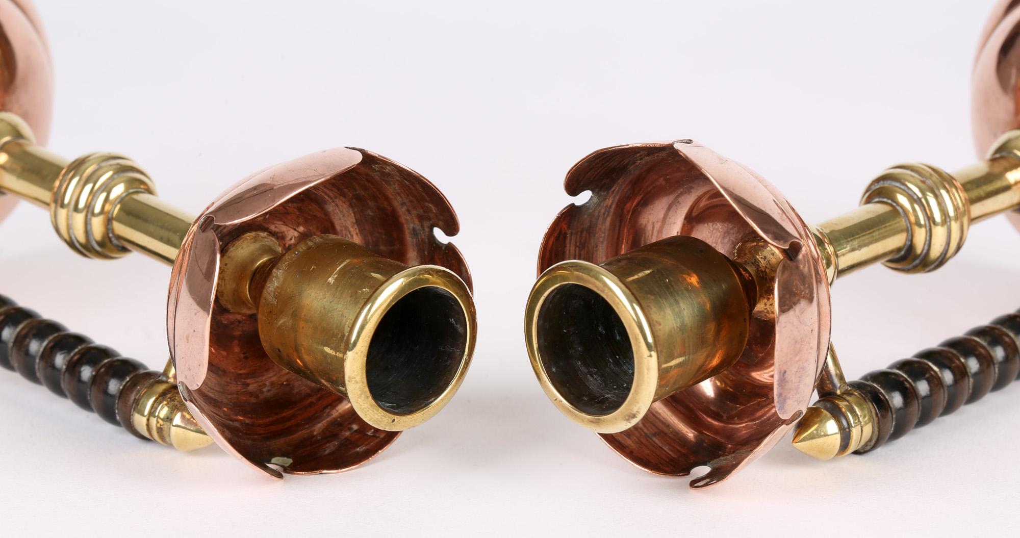 A very stylish pair Arts & Crafts copper and brass chambersticks after a design by Christopher Dresser and made by James Henry Stone of Birmingham, circa 1886. The chambersticks stand on rounded raised and shaped weighted copper bases with brass