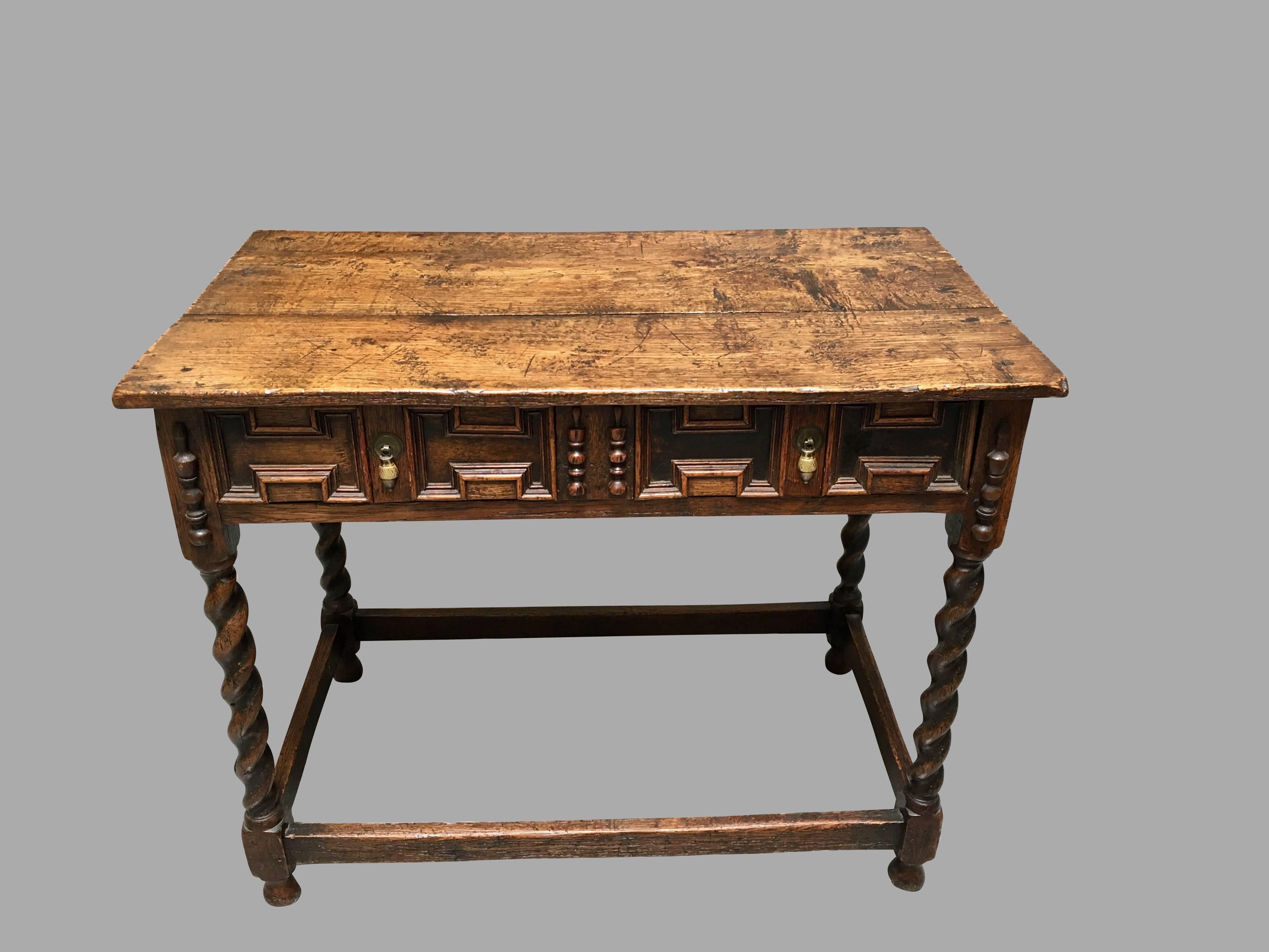 A James II period oak side table, the overhanging top above a long frieze drawer with panelled decoration, supported on barley twist legs joined by a box stretcher ending in bulb feet, circa 1680.