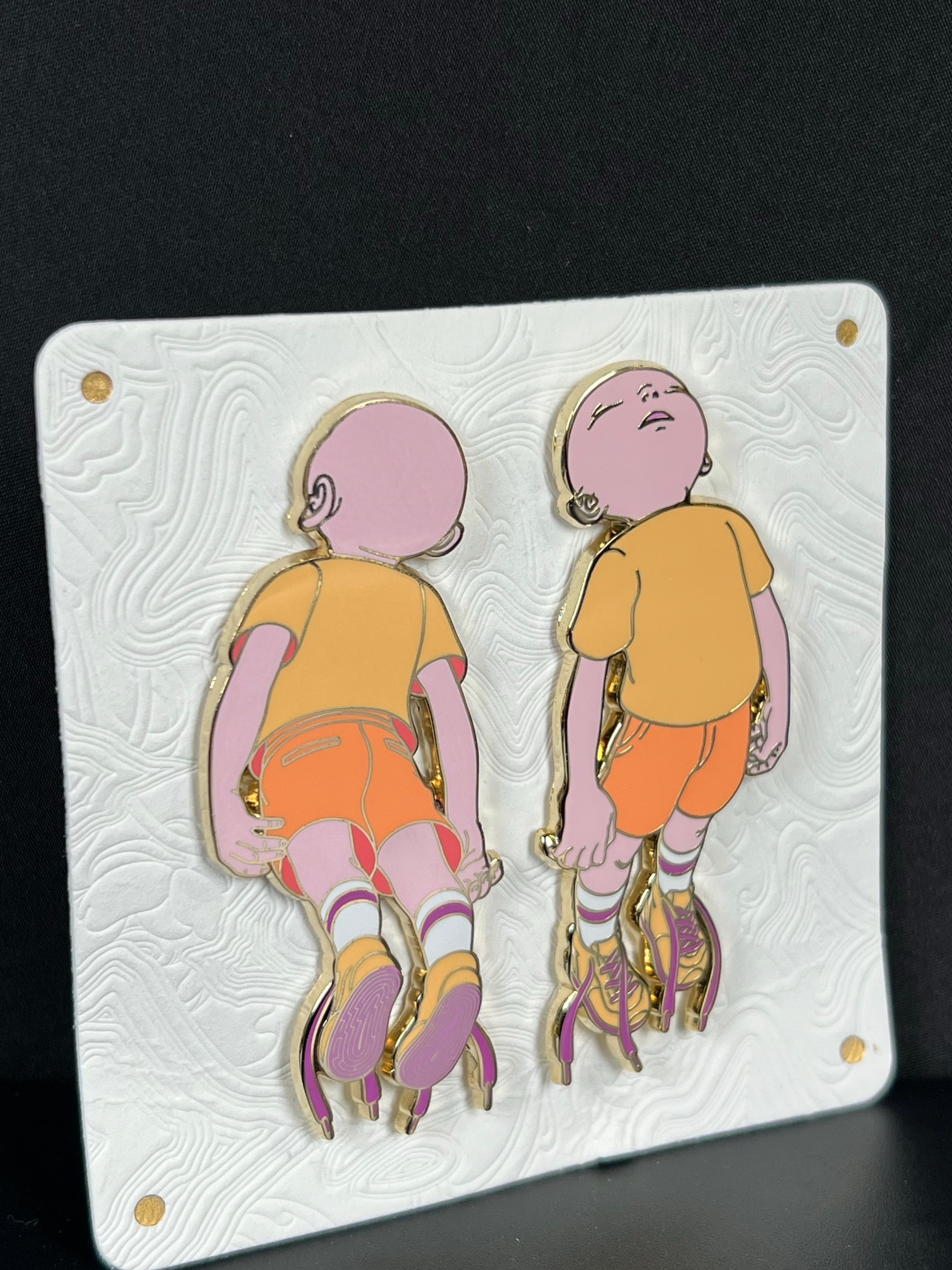 Descendants captures James Jean ( American - Taiwanese b.1979)  signature blend of surrealism and emotional depth. This limited edition enamel pin set features two ethereal childlike figures, rendered in vibrant hues of melon, tangerine, and rose,