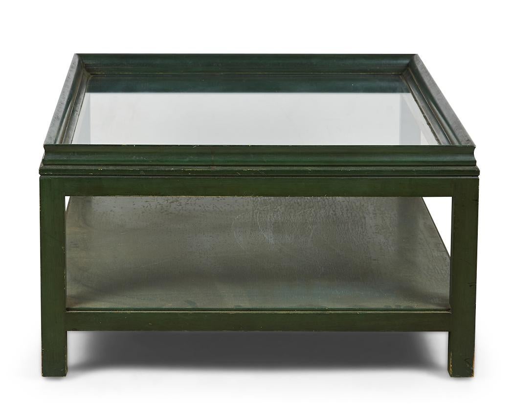 Table basse rectangulaire de style américain Mid-Century High Style (circa 1940) avec un cadre en bois laqué vert, un plateau en verre transparent et une étagère rectangulaire à traverse. (JAMES MONT)
