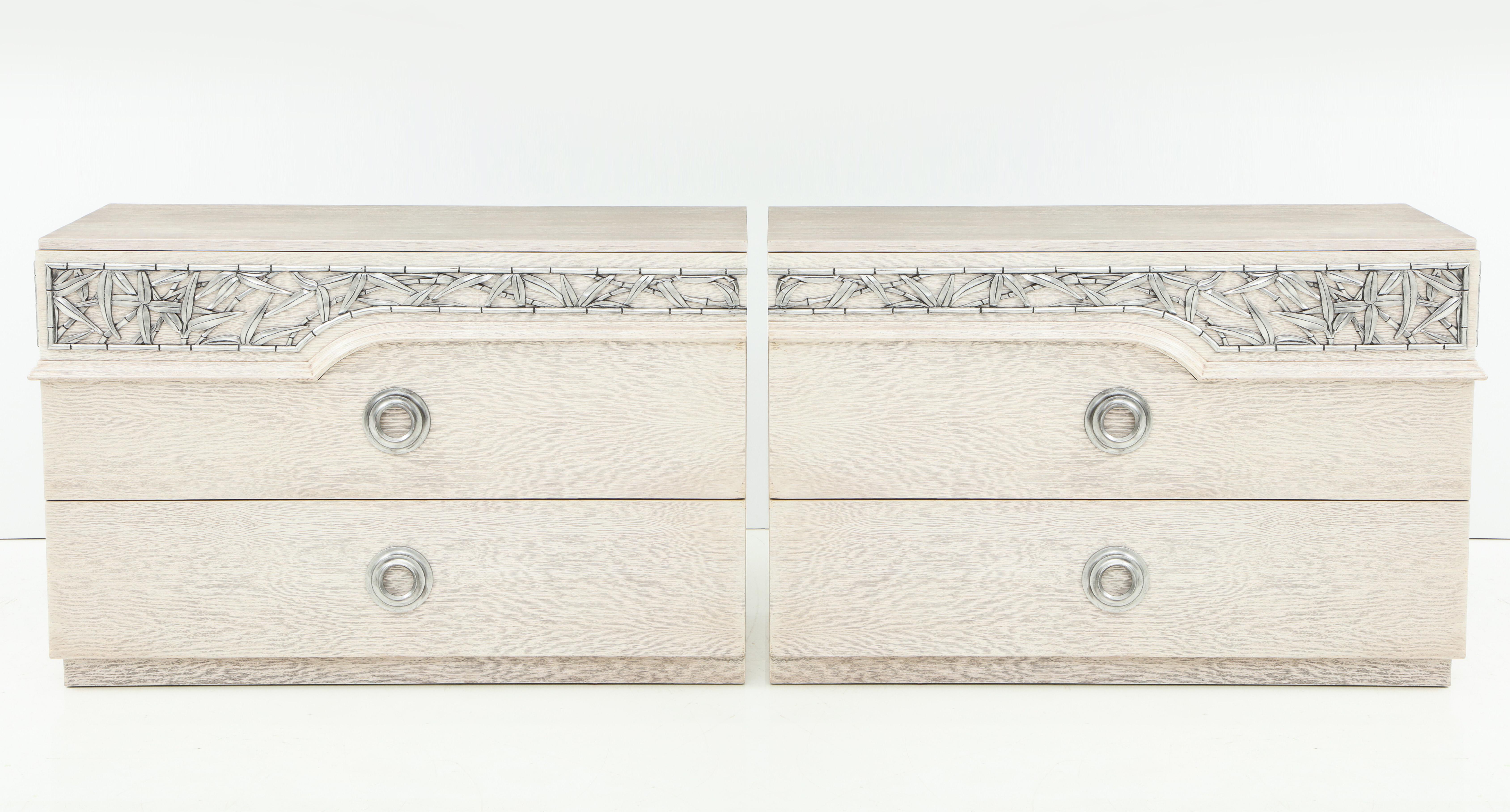 Pair of mint restored bleached/cerused oak dressers with chinoiserie inspired carved bamboo trim with an aged silver leaf finish. Stamped James Mont Designs. 
Each chest has 3 drawers. On display at 200 Lexington Avenue, 10th floor.