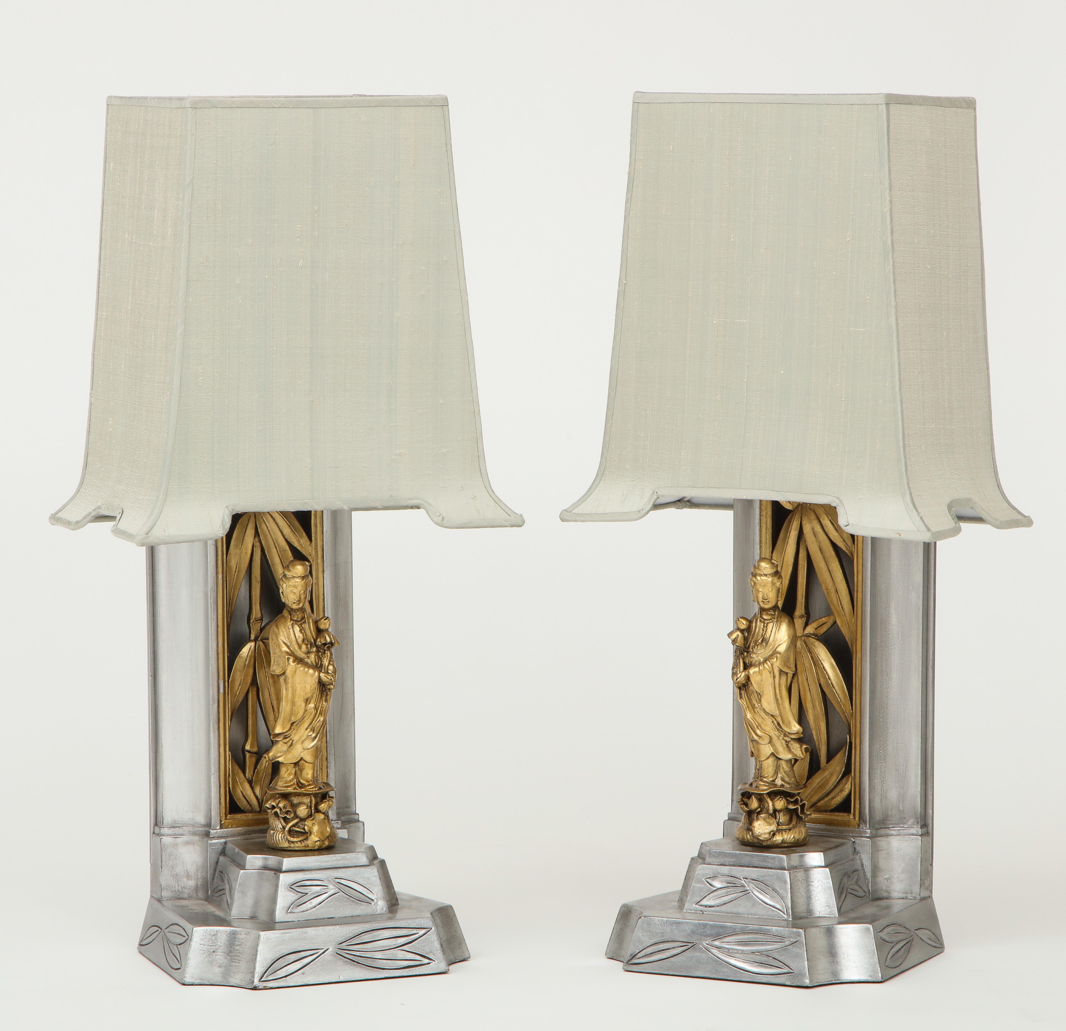Pair of James Mont gilded lamps each having a fluted and carved silver leaf base with contrasting gold leaf stylized bamboo leaves, and a gold gilded goddess figure. Original shades have been recovered in a silver shantung silk. Rewired for use in