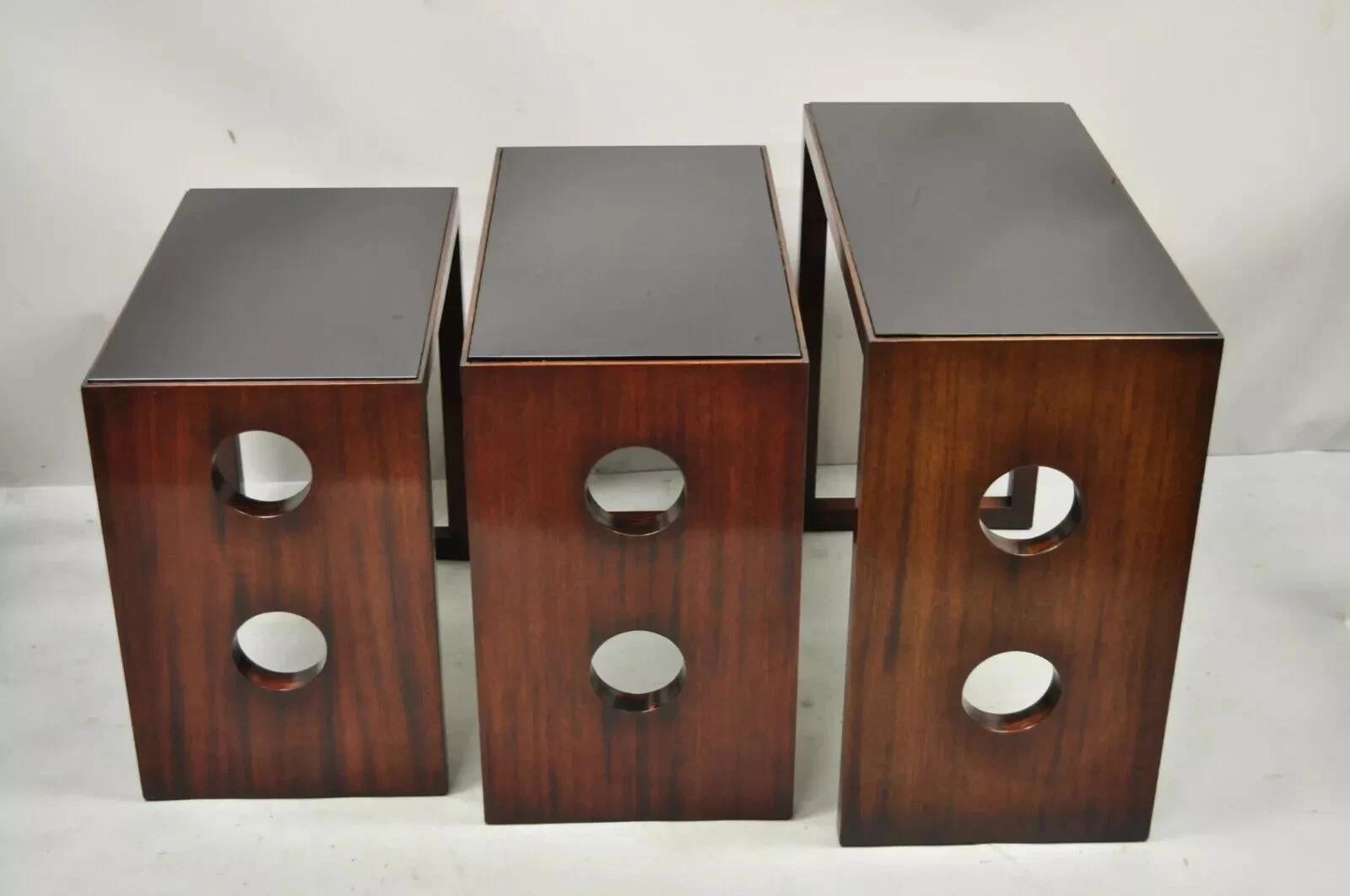 Vintage James Mont Mid Century Modern Mahogany & Glass Top Art Deco Nesting Side Tables. L'article se caractérise par des plateaux en verre noir, une taille progressive, un ensemble vintage très rare, des lignes modernistes épurées, une fabrication