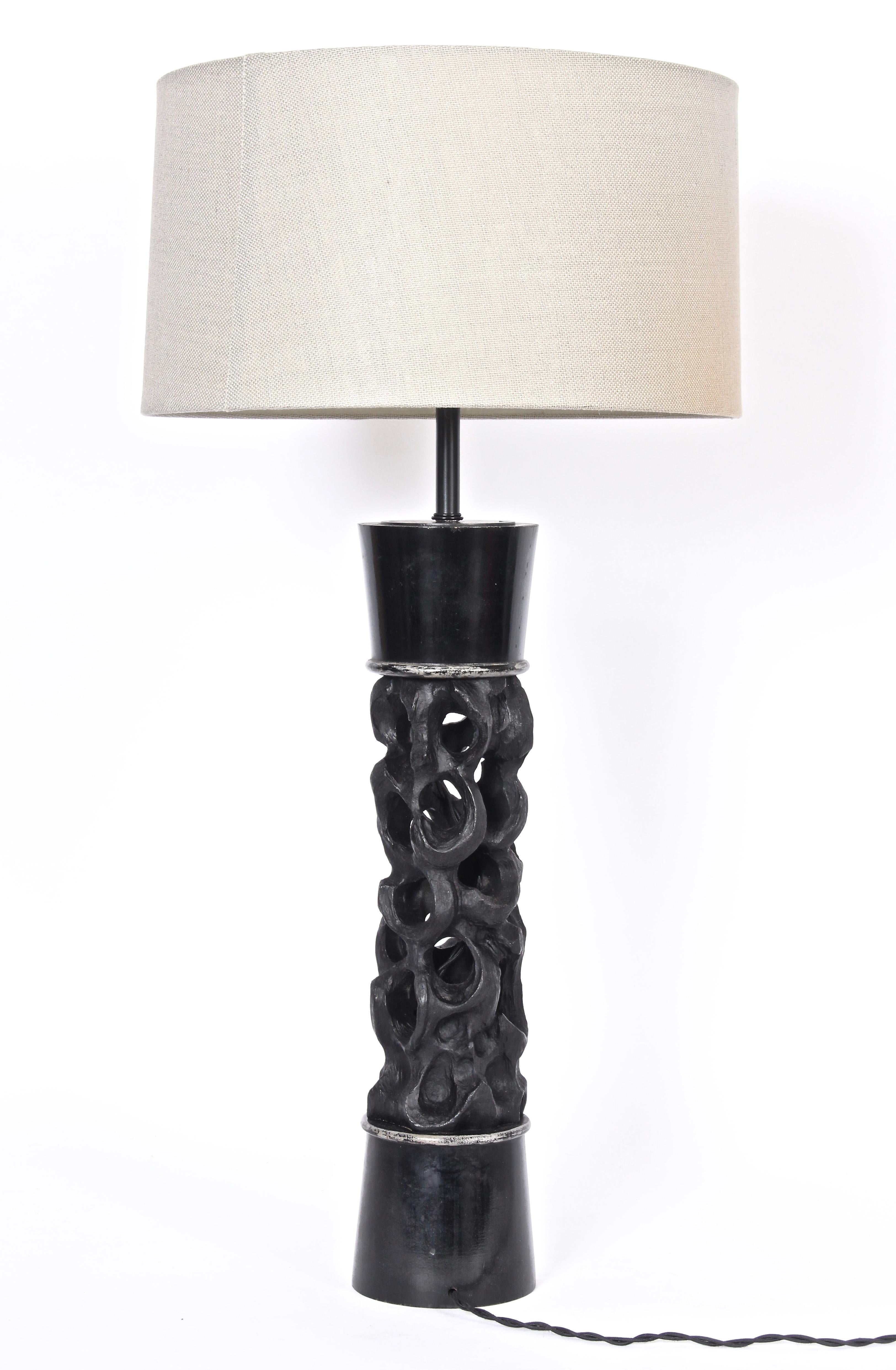 Monumental Handcrafted James Mont Table Lamp.  Featuring a slight hourglass form in blackened carved wood with silvered details. Small footprint. Shade shown for display only (10 H x 17 D top x 18 D bottom).  Adjustable double sockets. 34 H to top