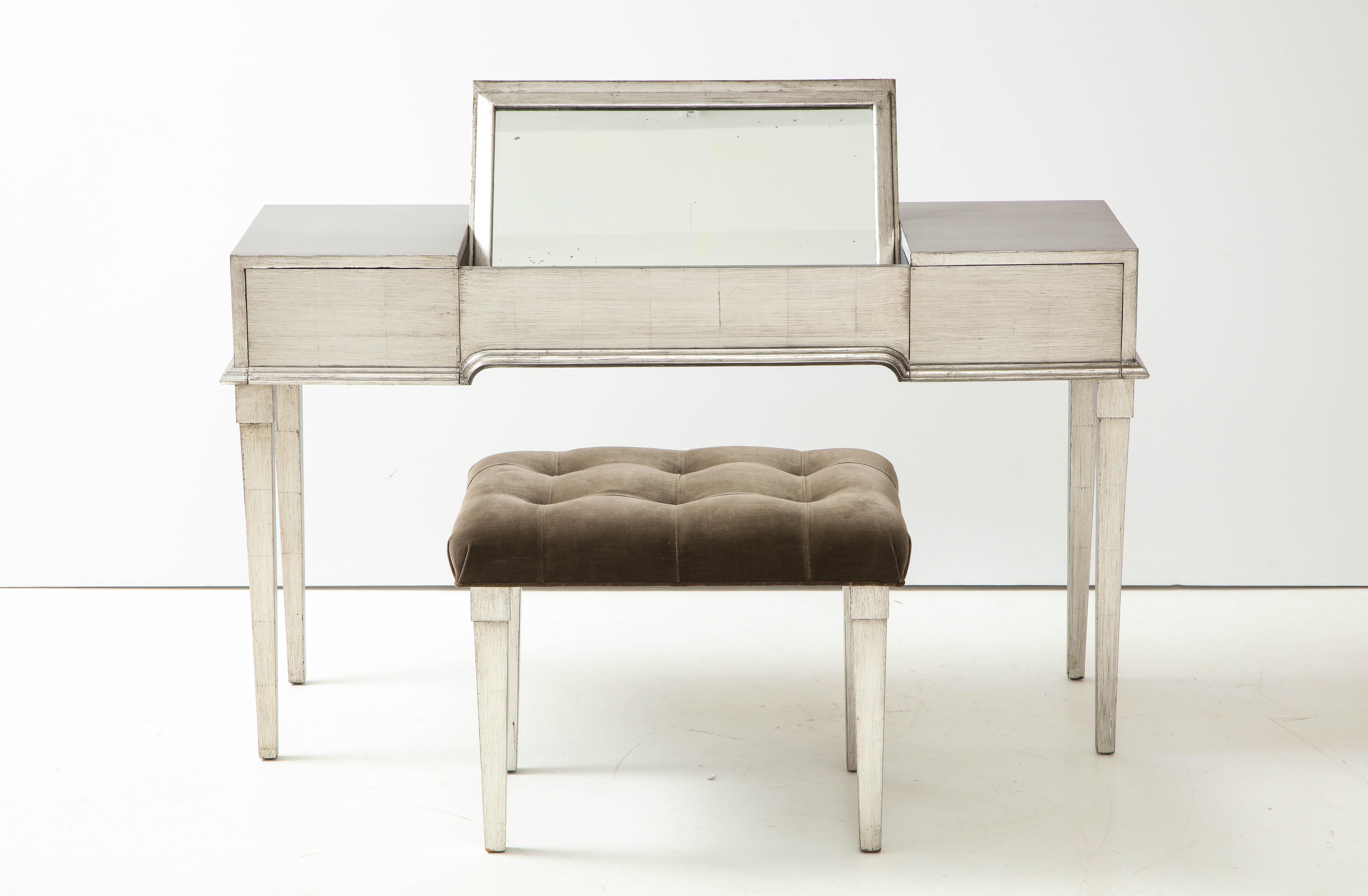 Elegant glazed silver leafed vanity / desk by James Mont.
The vanity has been newly restored with a glazed silver leaf finish and the bench has been
newly reupholstered in a taupe / brown velvet fabric.
