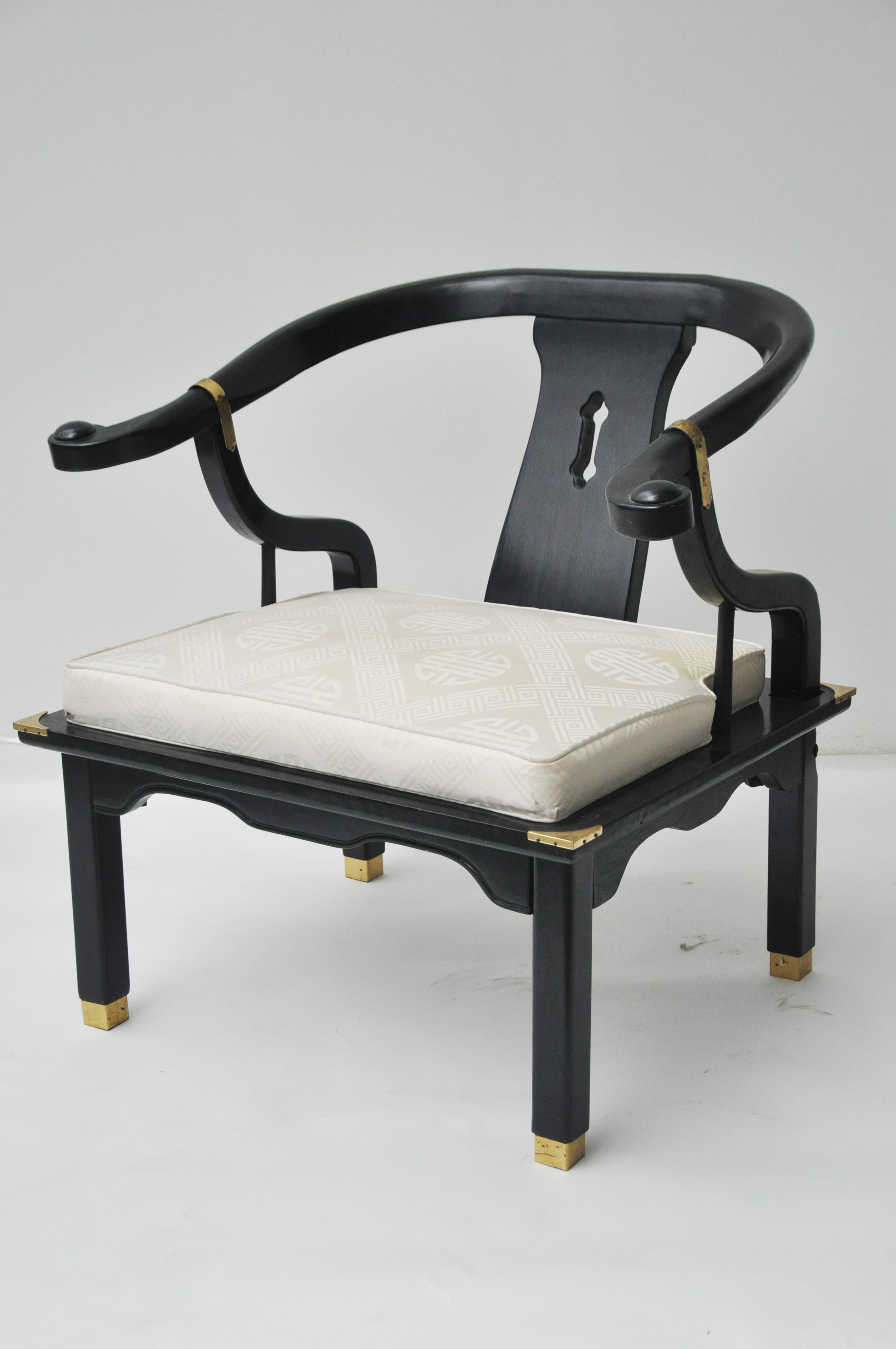 Chinoiserie Style Chinese black horseshoe club chair. Chair has brass detailing. This Ming style chair had a plastic cover over the chair cushion so the fabric is in excellent condition. 
