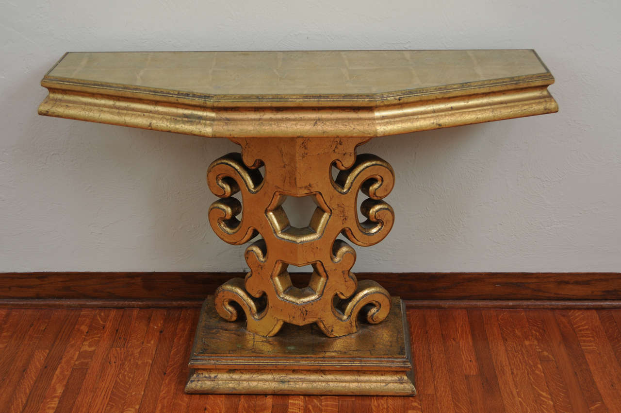 This stylish and chic console table dates to the mid-20th century and is very much in the style of pieces created by James Mont and could easily fit into an interior design by Tony Douquette. The piece is finished in a dark gold Floreninte