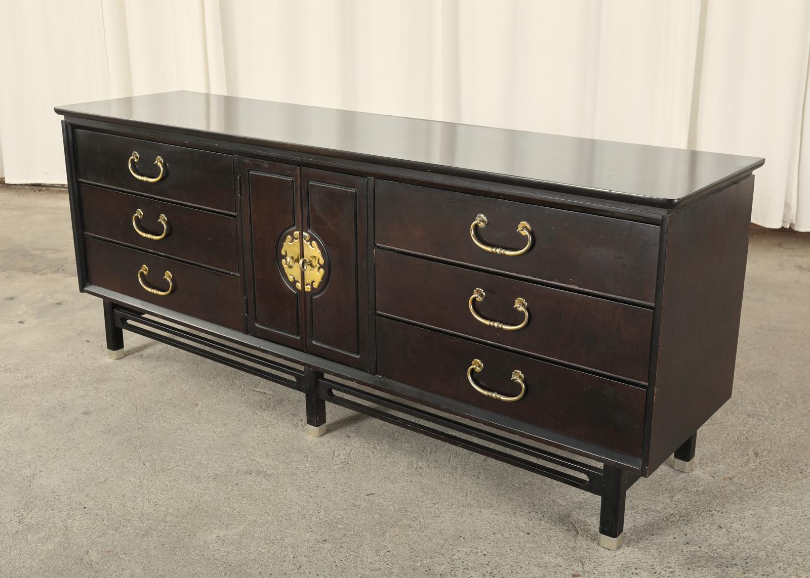 Dramatic Hollywood Regency dresser or credenza featuring a near ebony lacquer finish. Designed in the mid-century chinoiserie Asian inspired taste. Made in the manner and style of James Mont. The case has six large storage drawers with brass