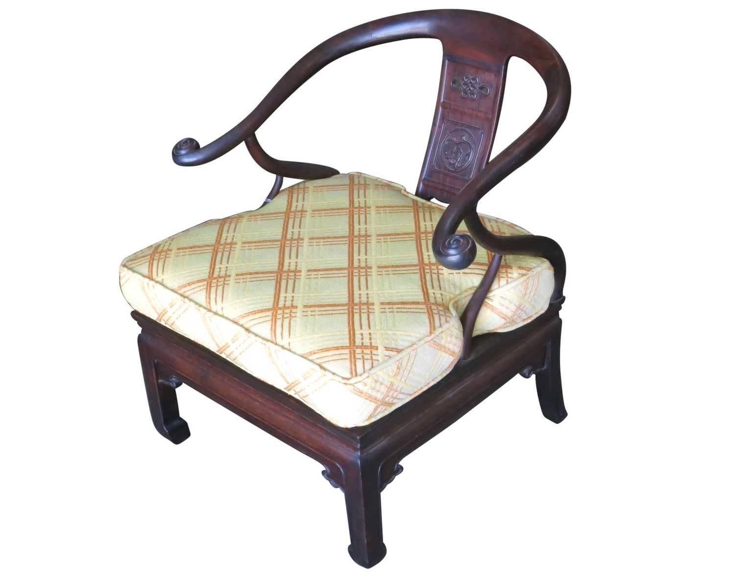 Superbe paire de fauteuils asiatiques en fer à cheval de style James Mont. 

Tous deux possèdent un cadre en bois teinté foncé avec des reliefs et des décorations sculptés à la main. Les coussins d'assise multicolores présentent un superbe motif